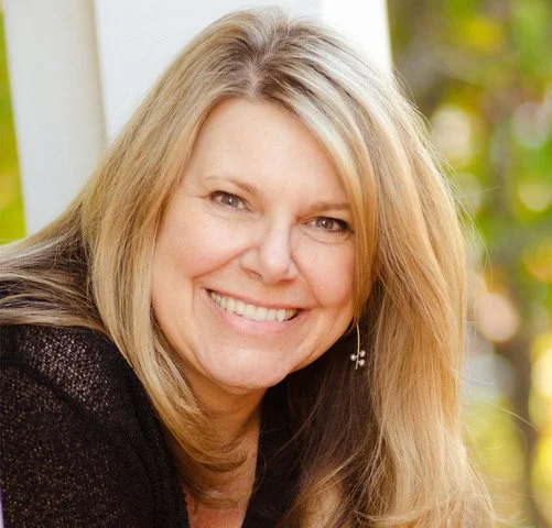Nancy Stubbs is smiling against a neutral, green background in a black shirt.