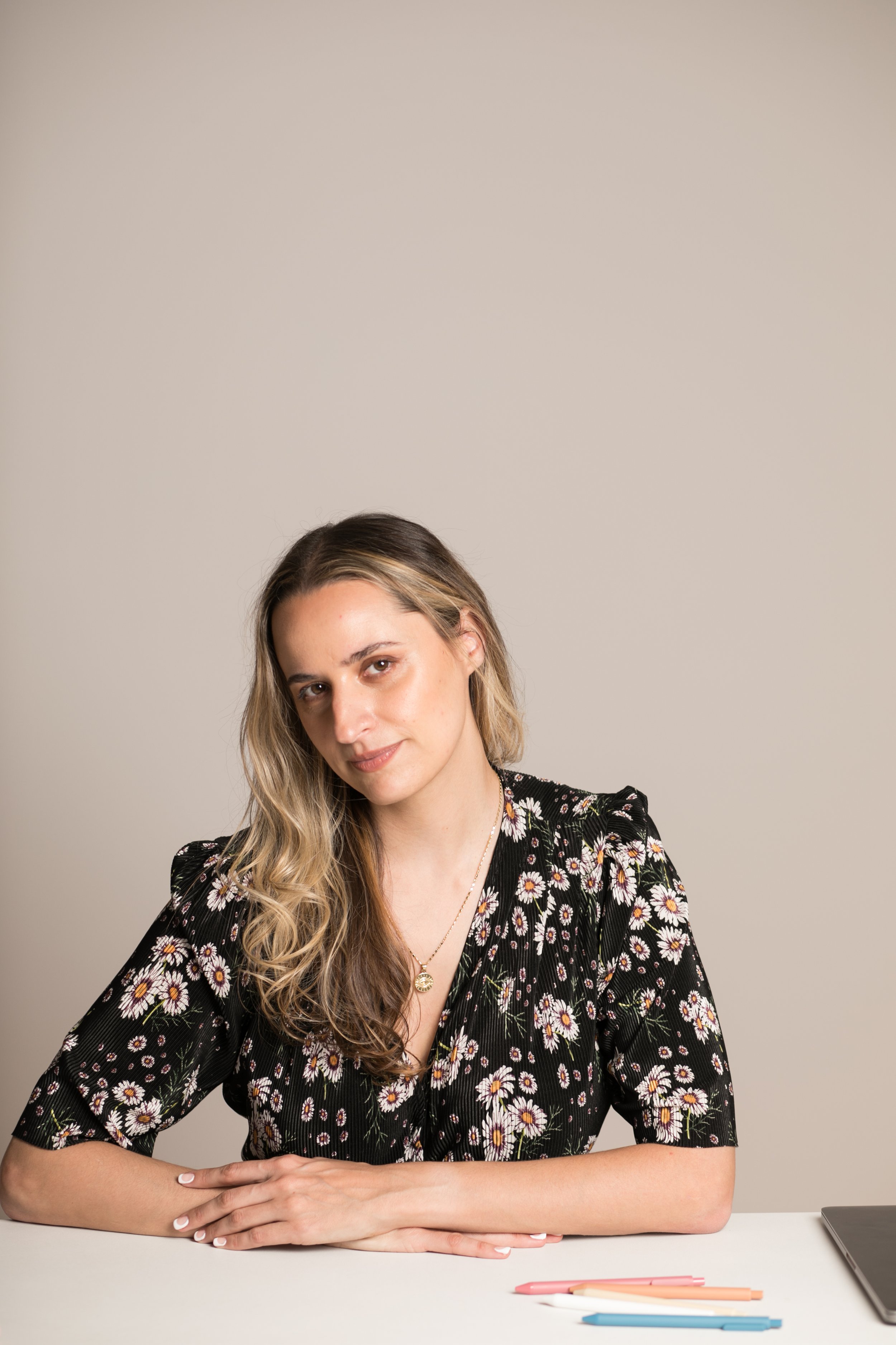 dani herrera is smiling against a tan background, wearing a patterned black blouse.