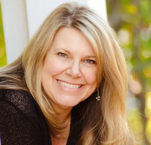 Nancy Stubbs is smiling against a neutral, green background in a black shirt.
