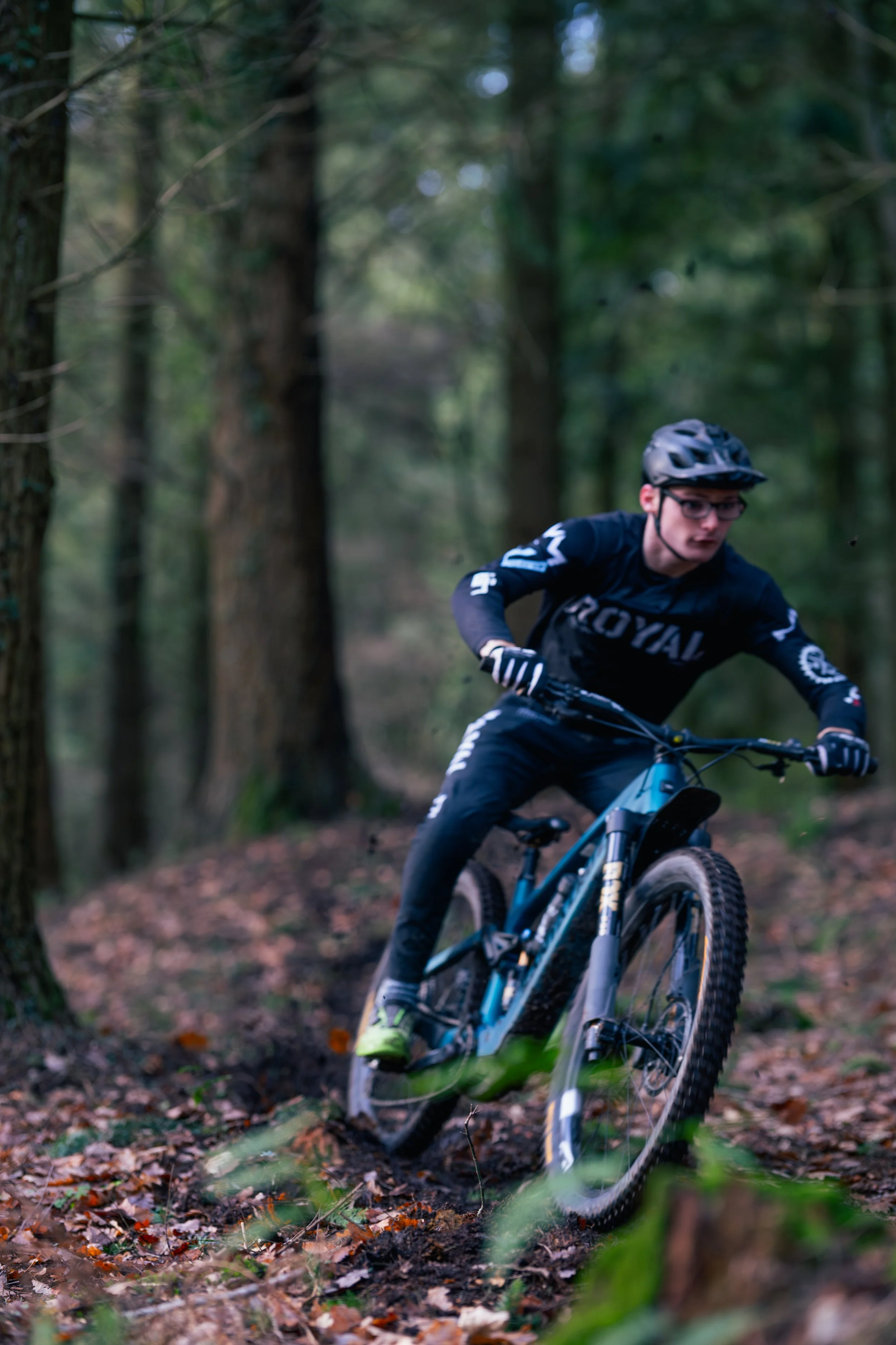 A person mountain biking on a trail through a forest.