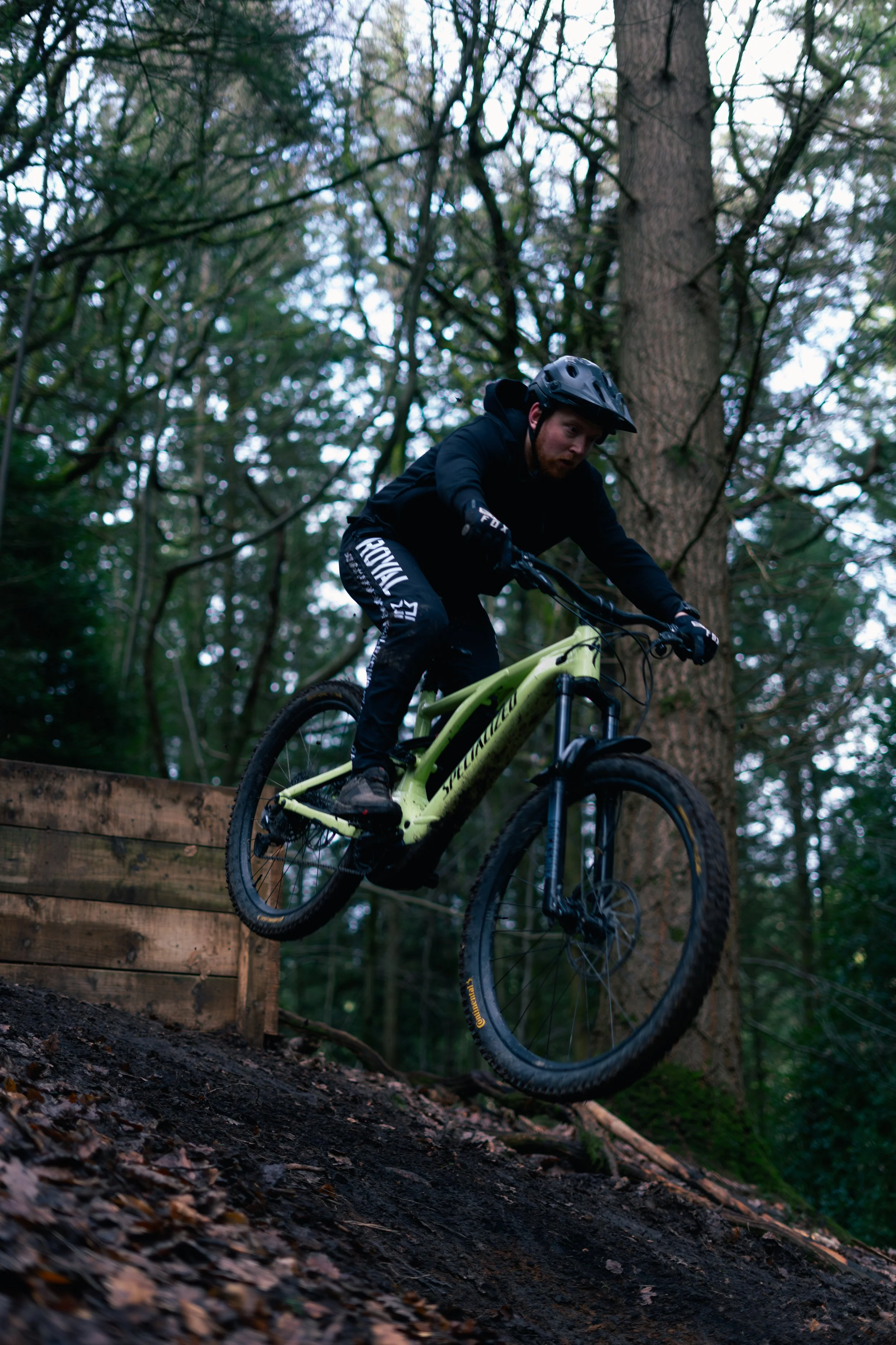 A man wearing a helmet and black clothing riding a mountain bike down a dirt trail in a forest.