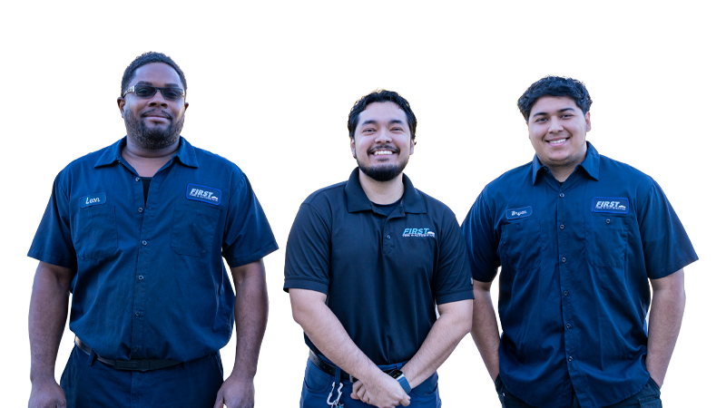 Three young men in matching blue shirts with FIRST logos, smiling and standing side by side against a light-colored background.