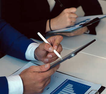 Business professionals using digital tablets and taking notes during a meeting.
