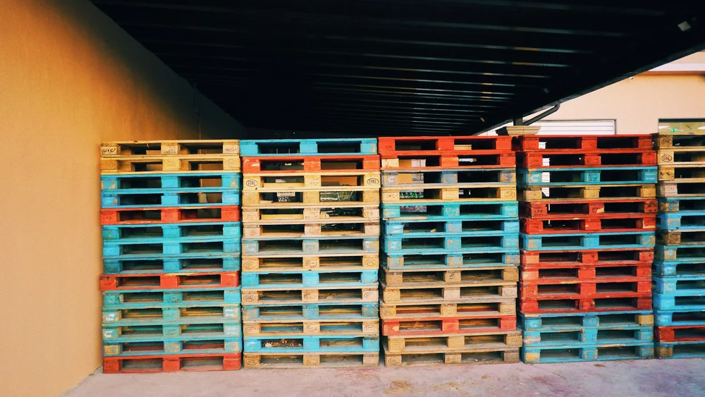 Used wooden pallets stacked against a warehouse wall.