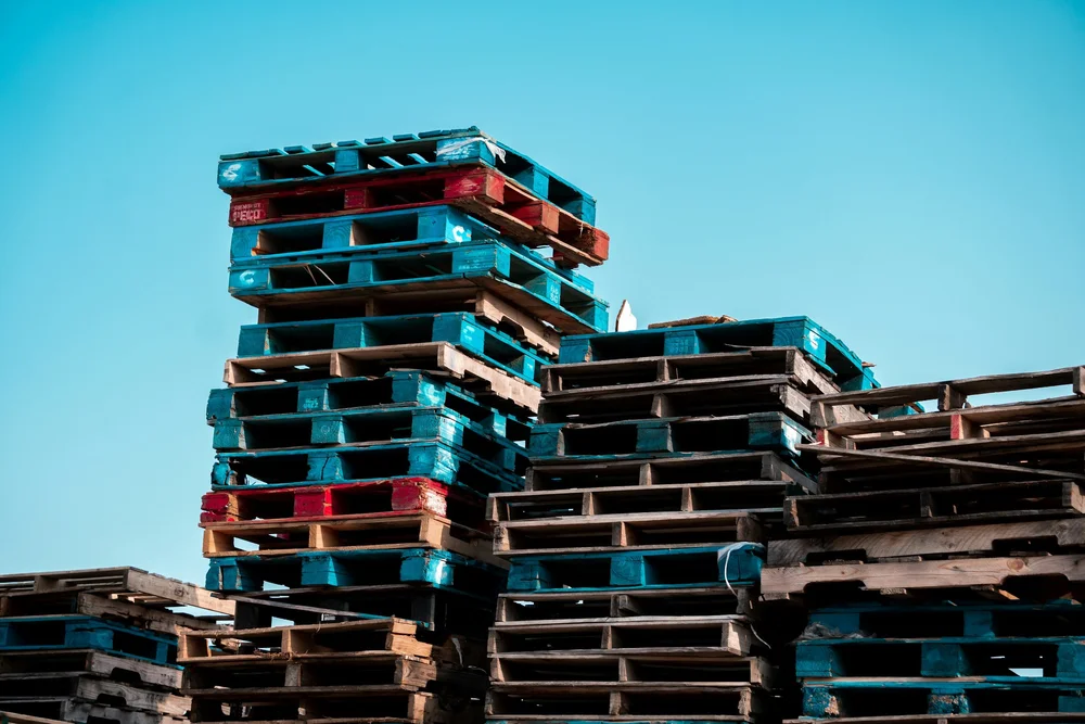 Recycled wooden pallets stacked outdoors, ready for collection.