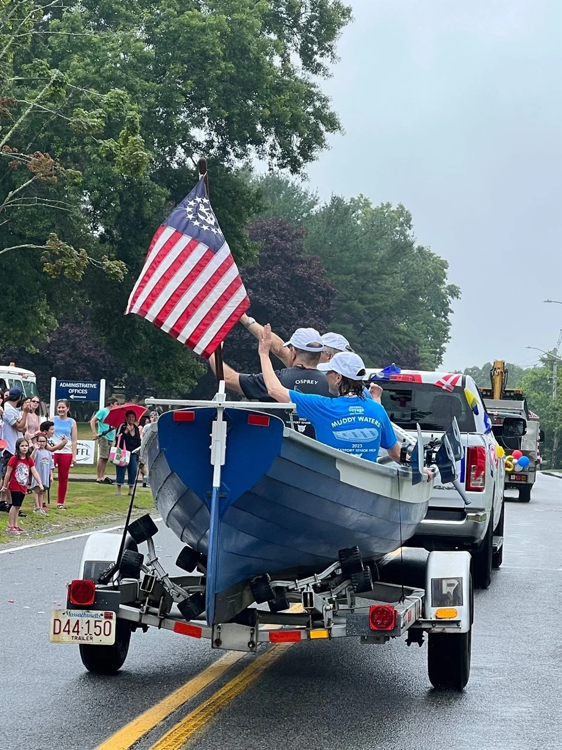 American flag waving on a boat with water and distant shoreline in the background.