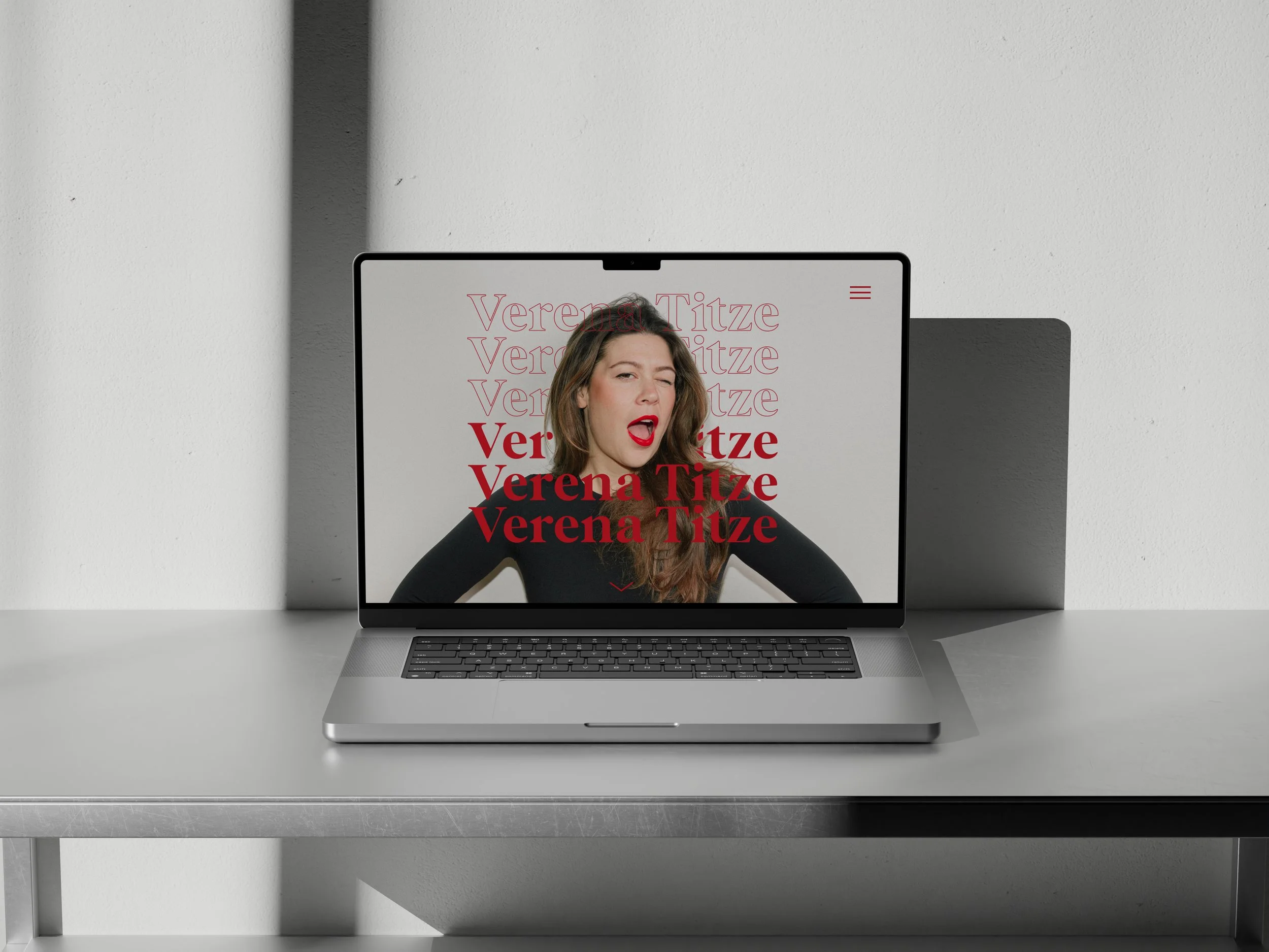 Ein offener Laptop auf einem Tisch zeigt eine Webseite mit einem Foto einer Frau, die lacht. Über dem Foto sind mehrfach der Name 'Verena Titze' und in roten Buchstaben der Name hervorgehoben.