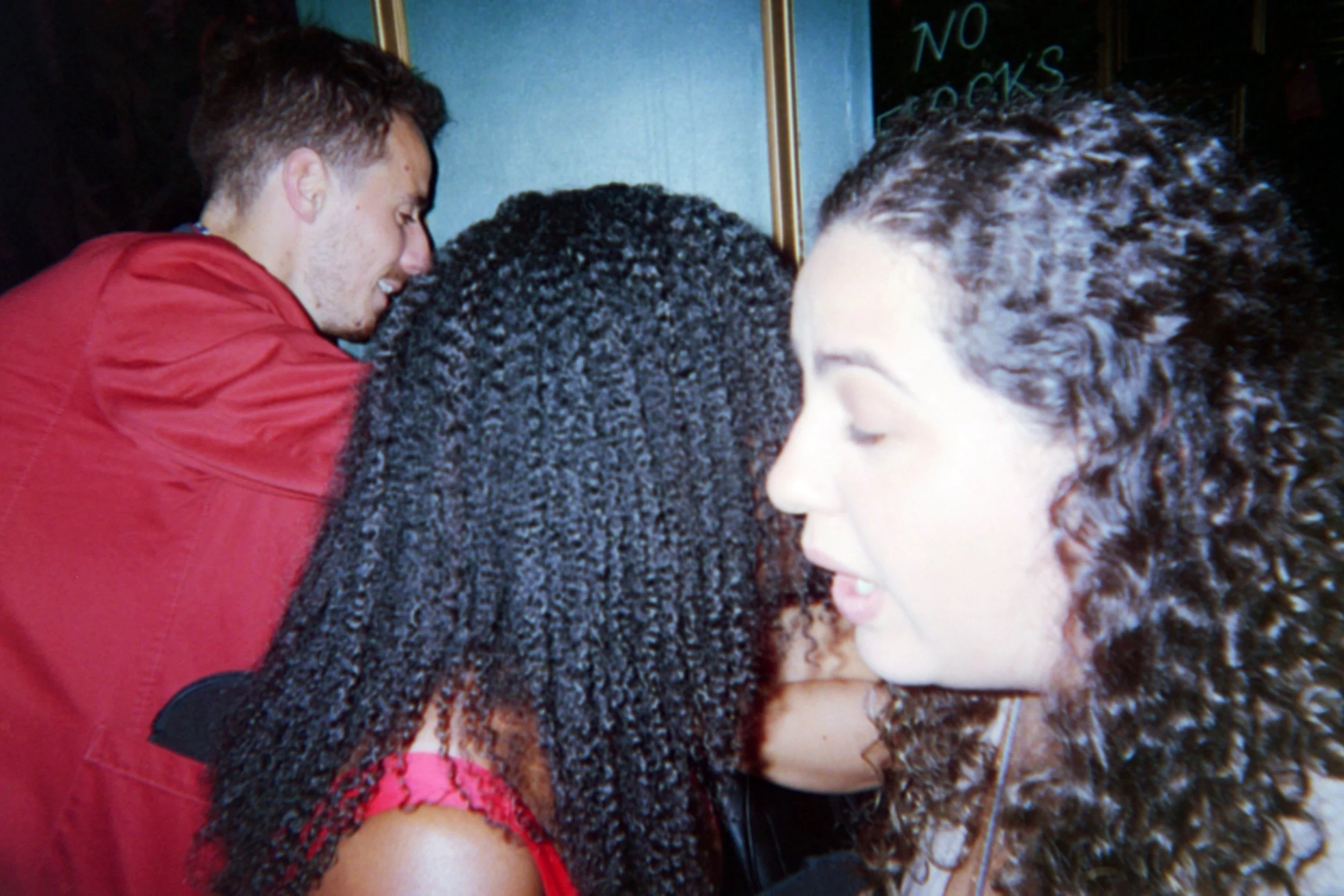 Group of people closely together, some with closed eyes, in a social setting.