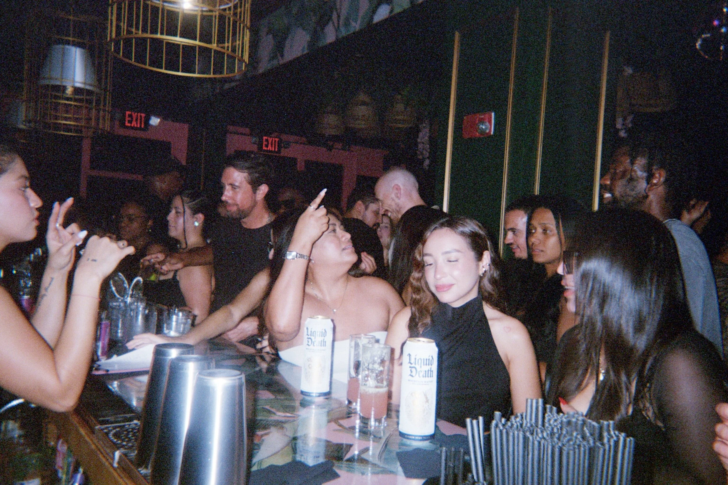 People socializing at a bar or nightclub with drinks and a lively atmosphere.