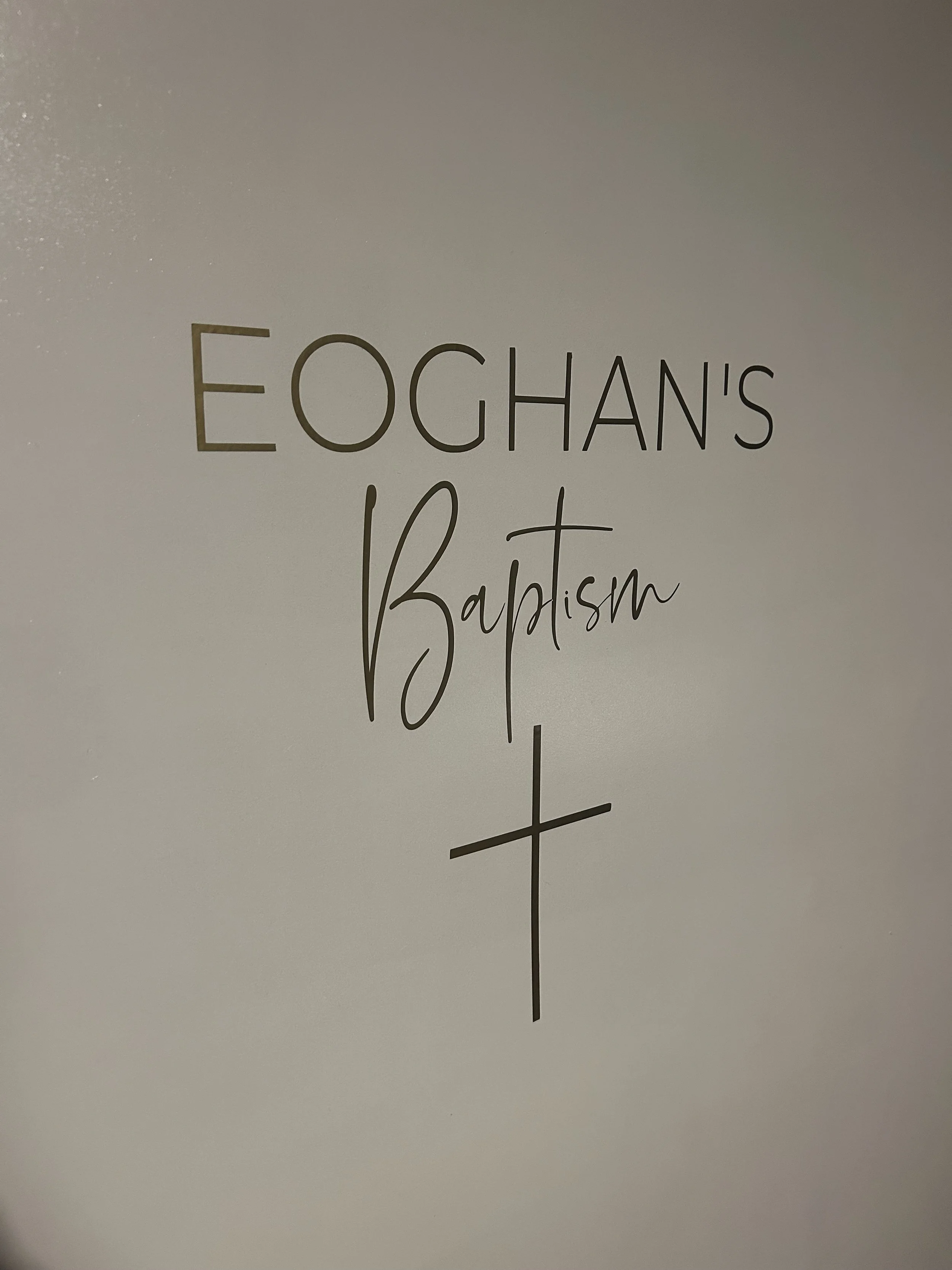 Wall decoration reading "Eoghan's Baptism" with a Christian cross below the text.