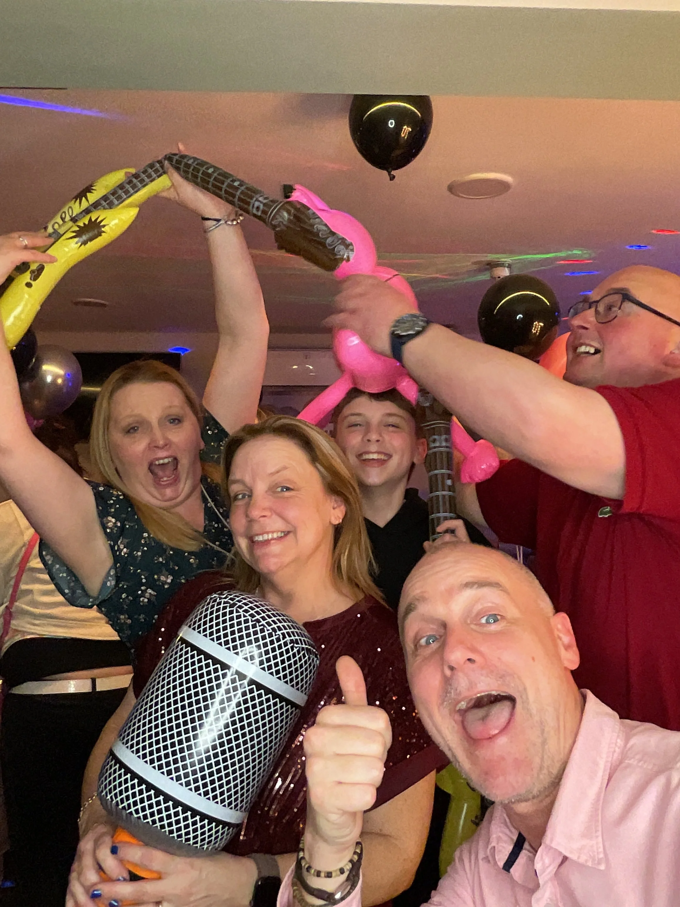 Group of people celebrating at a party with balloons and party decorations.