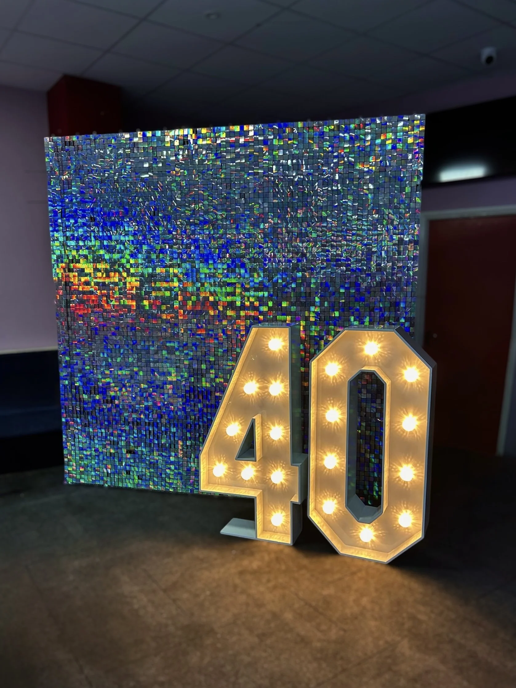 Illuminated marquee numbers 40 next to a iridescent mosaic wall.