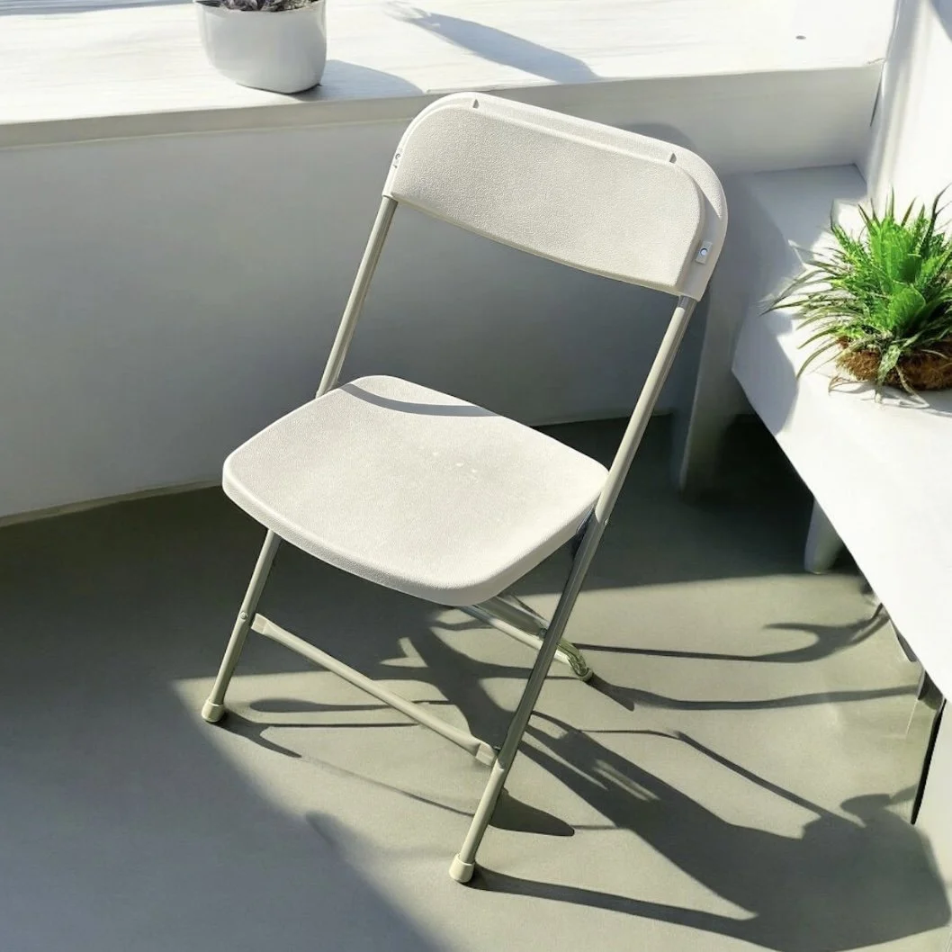 Outdoor backyard setup with a large white folding table, nine beige chairs, a gray canopy tent, and a wooden shed. There's a fence, trees, and grass.