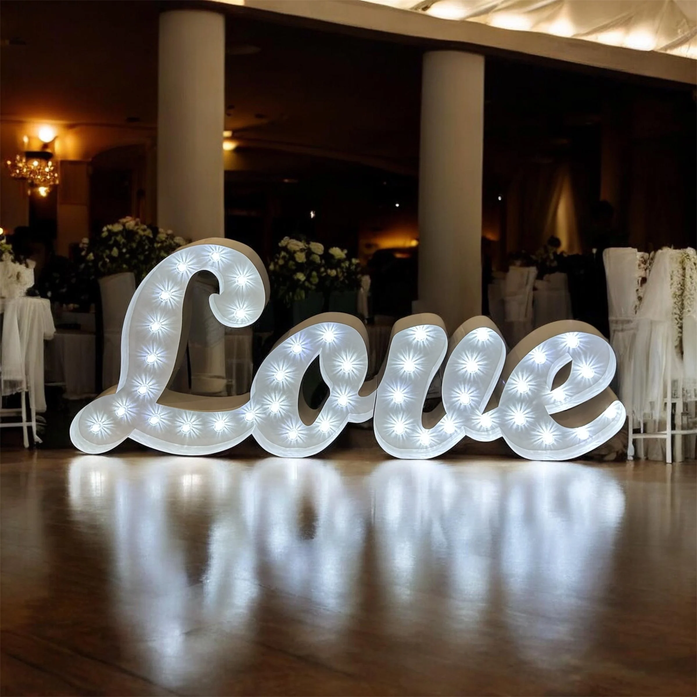 Decorative illuminated letters on a wooden floor in a dimly lit event space.