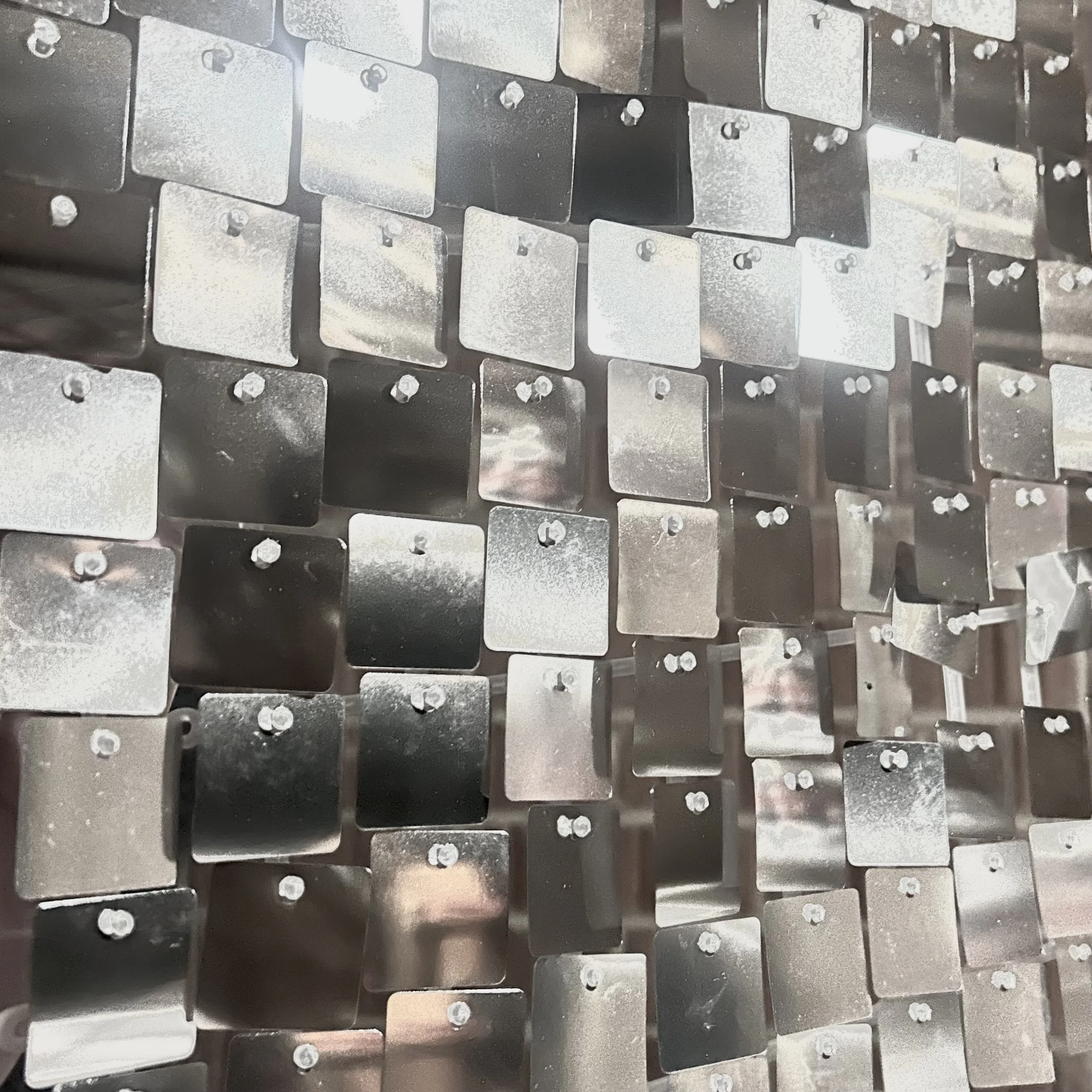 A close-up view of a large number of metal plates and bolts, arranged in a grid-like pattern, with some plates showing signs of wear or oxidation.