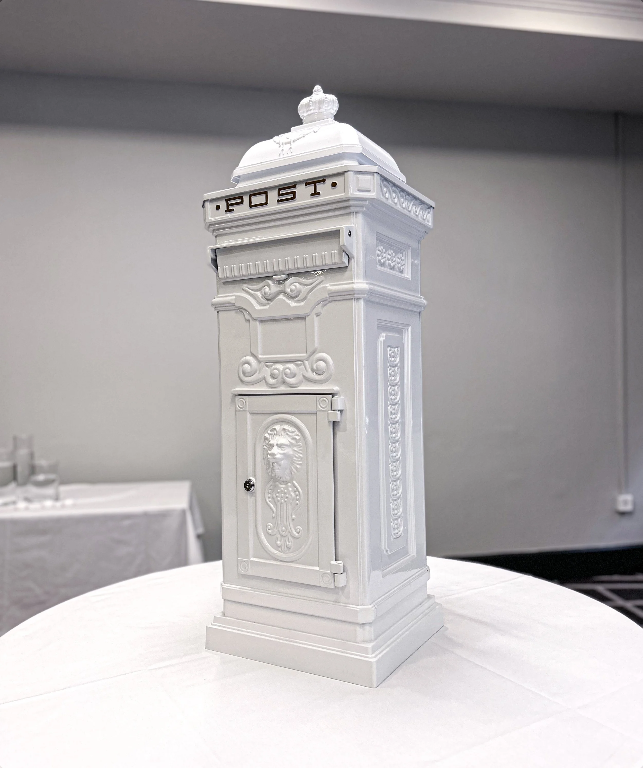 White model of a vintage mailbox with decorative elements and the word 'POST' on top, displayed on a table.
