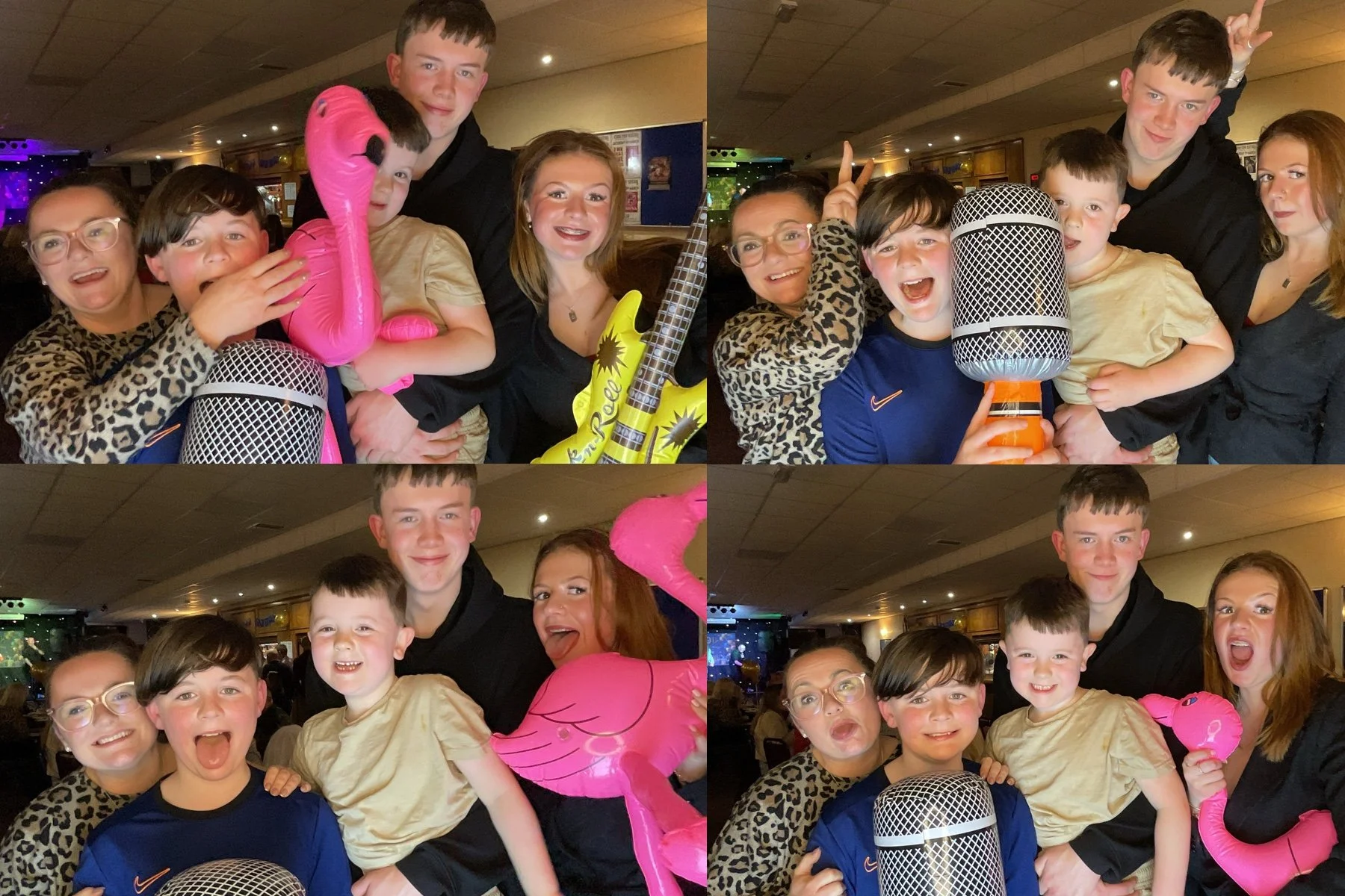 A group of children and two adults celebrating indoors with balloons, a pink flamingo shaped balloon, and a large fake microphone, smiling and making playful gestures.