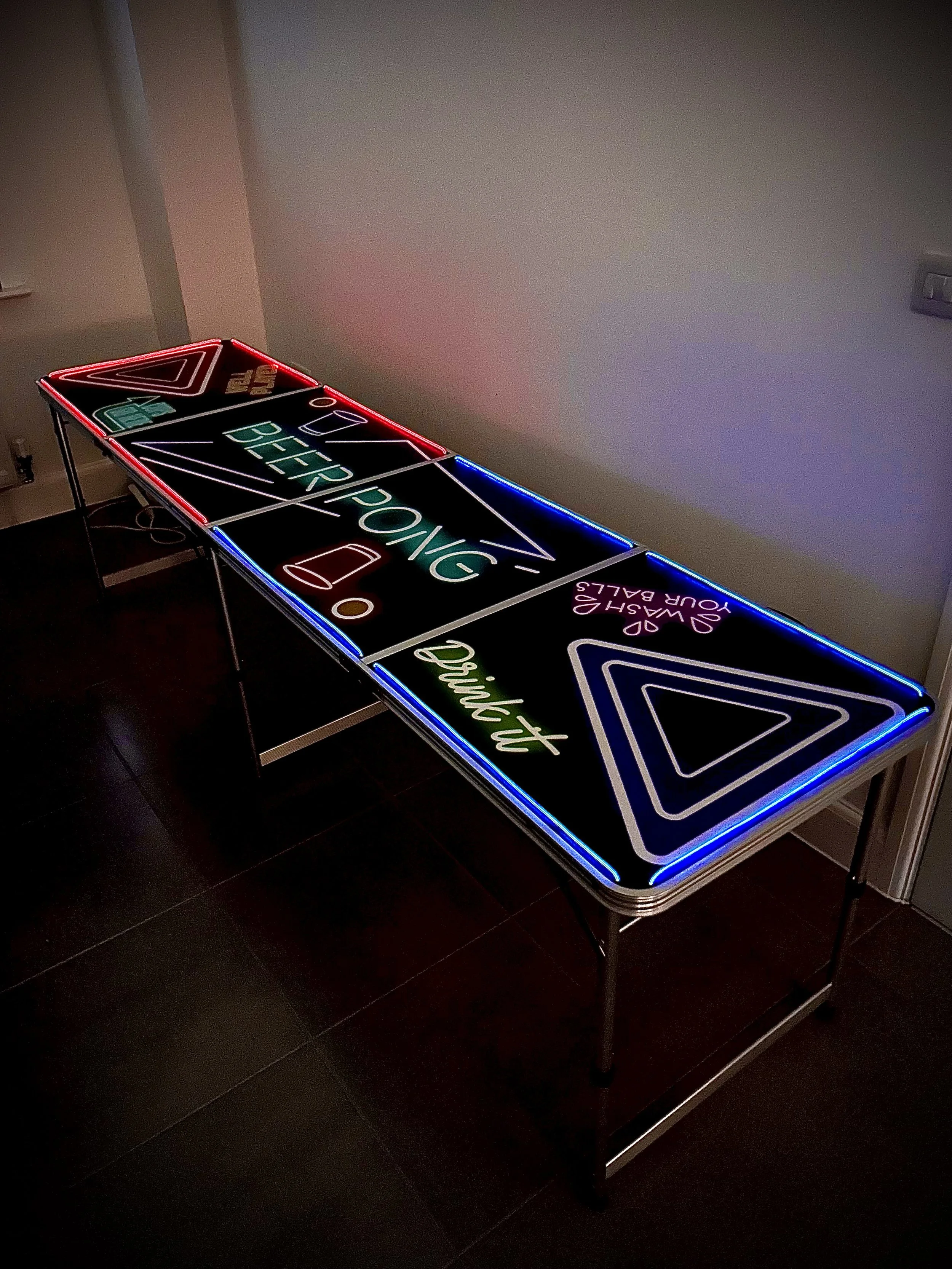 Colorful neon sign displaying “OB” and “BÜRO POLICE,” with additional unreadable text, placed on a black table against a plain wall.