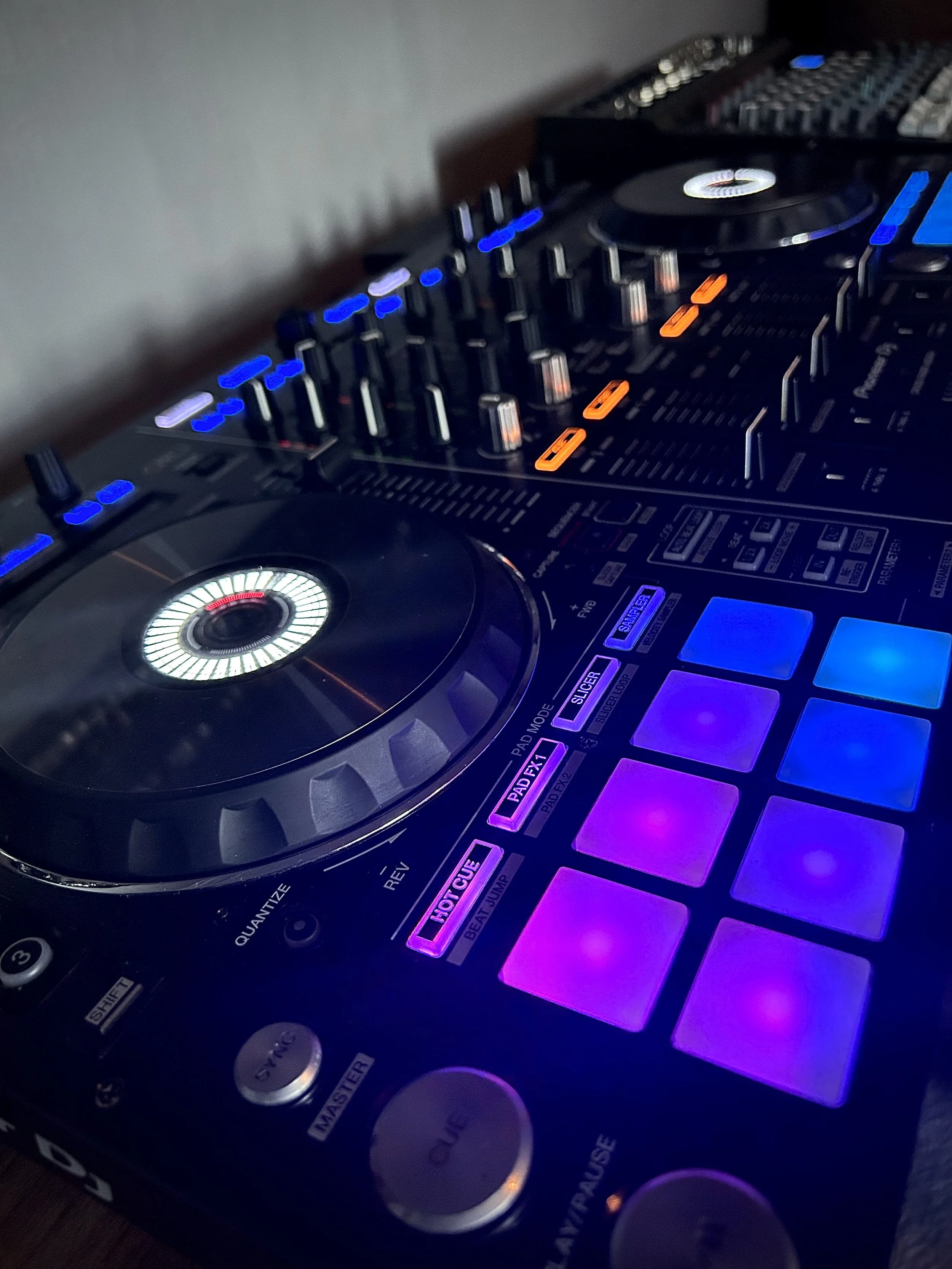 DJ controller with illuminated pads, knobs, and buttons, used for mixing music.