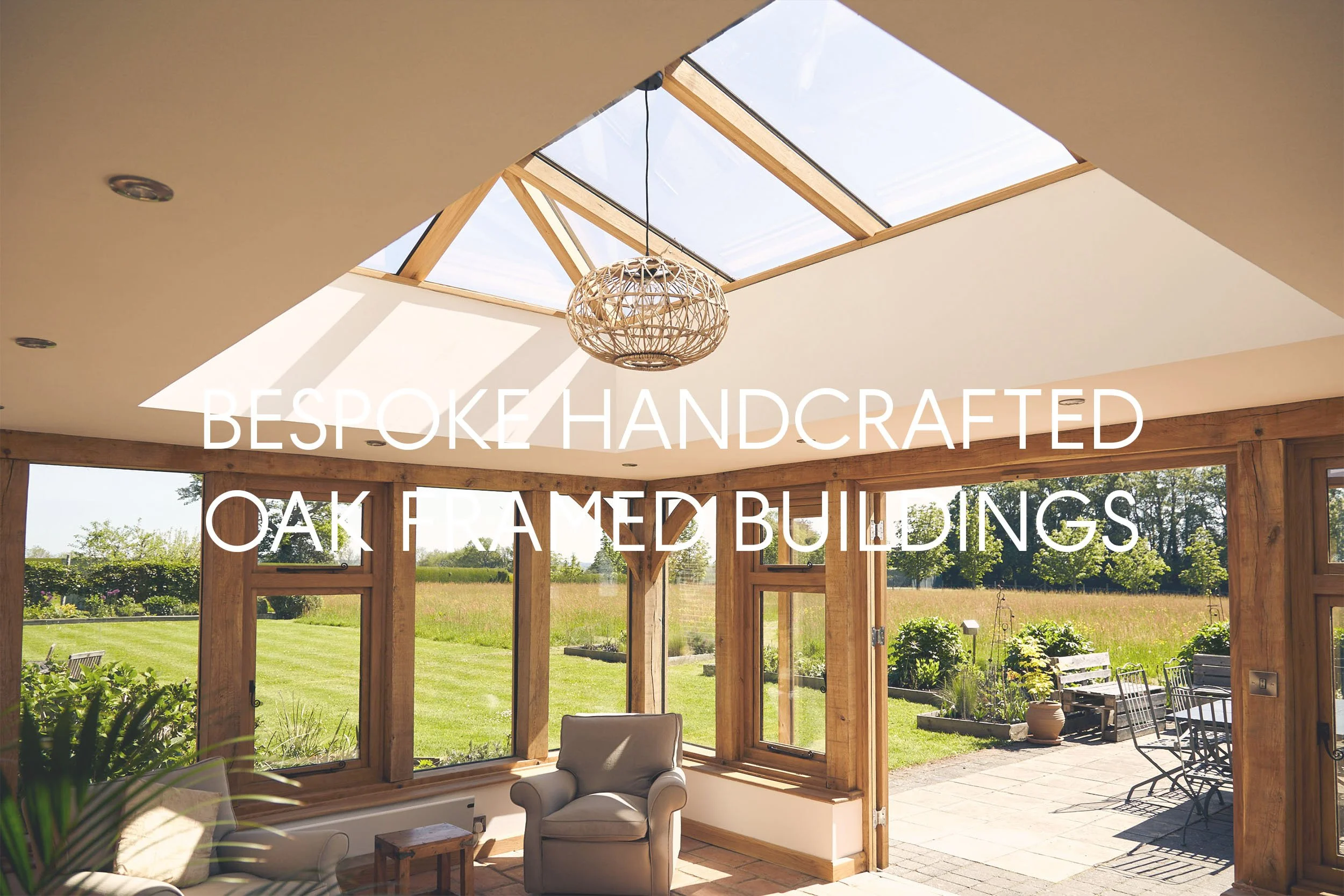 Sunroom in an oak framed orangery extension, with large oak skylight, timber framing, and glass doors leading to an outdoor patio, with a beige couch and decorative pillows inside.
