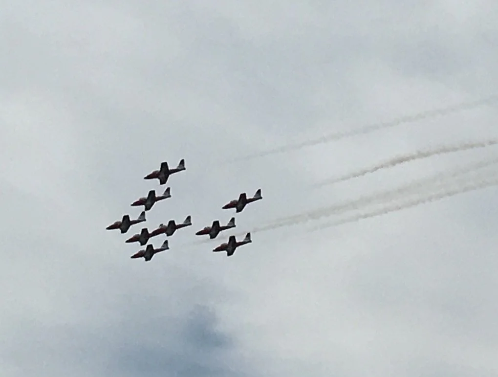 A formation of eight fighter jets flying in the sky, trailing smoke behind them.