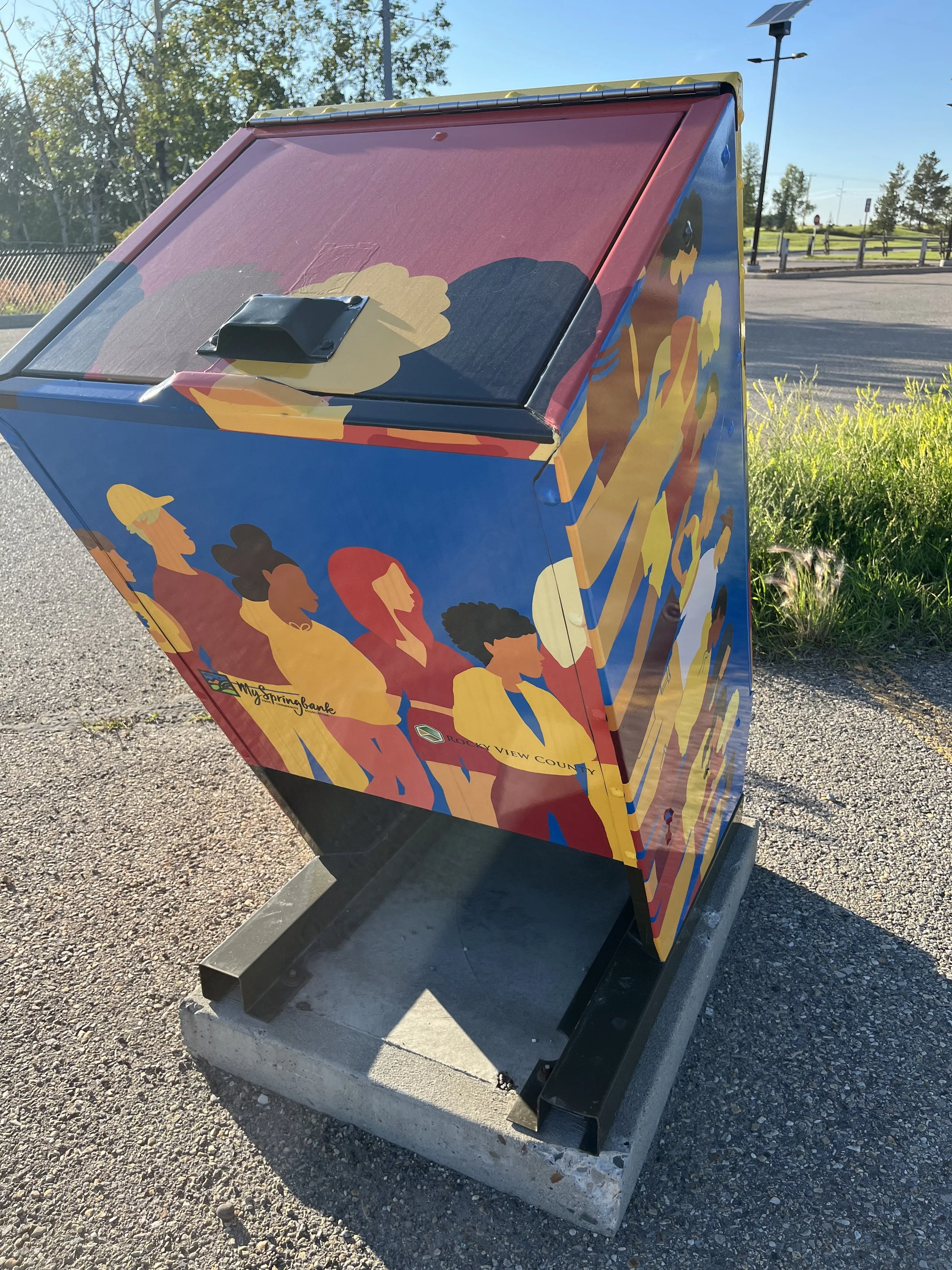 A colorful outdoor kiosk painted with illustrations of diverse women and the words 'Rocky View County' at the bottom.