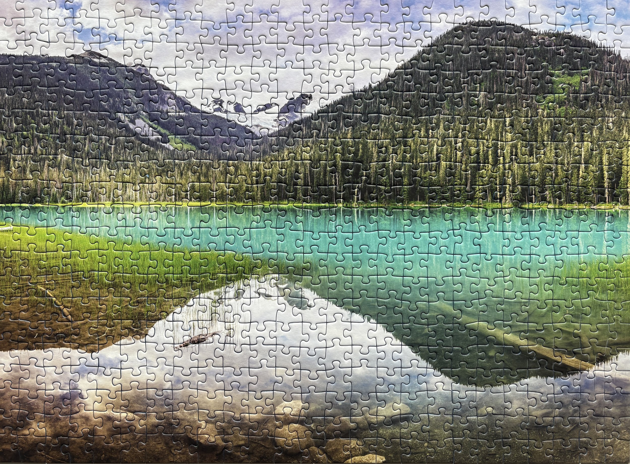 A finished landscape puzzle featuring a lake and mountain scene from Joffre Lakes Park