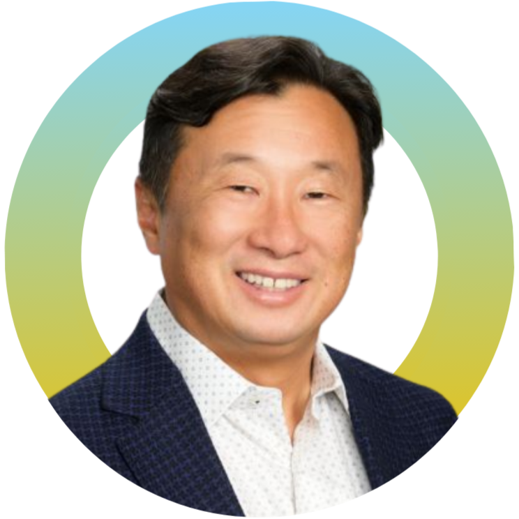 A headshot of a man with dark hair, wearing a white shirt and a dark blazer, smiling.