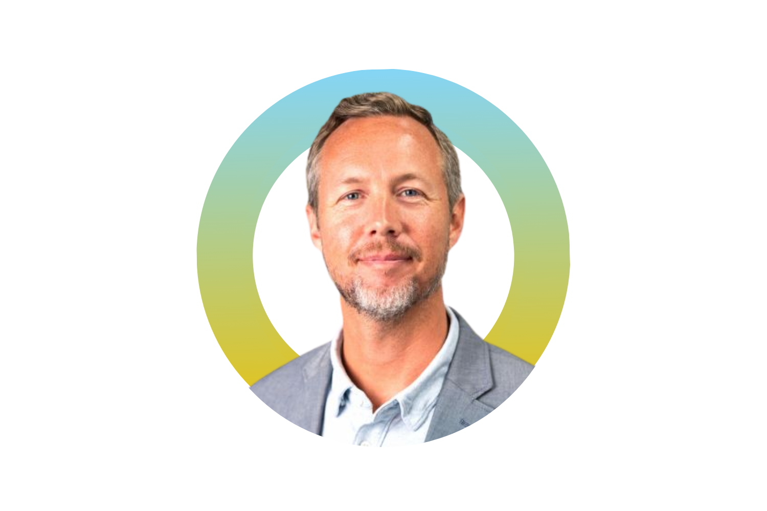 A man with short, light brown hair, some facial hair, wearing a gray blazer and a light blue shirt, smiling slightly against a colorful geometric background.