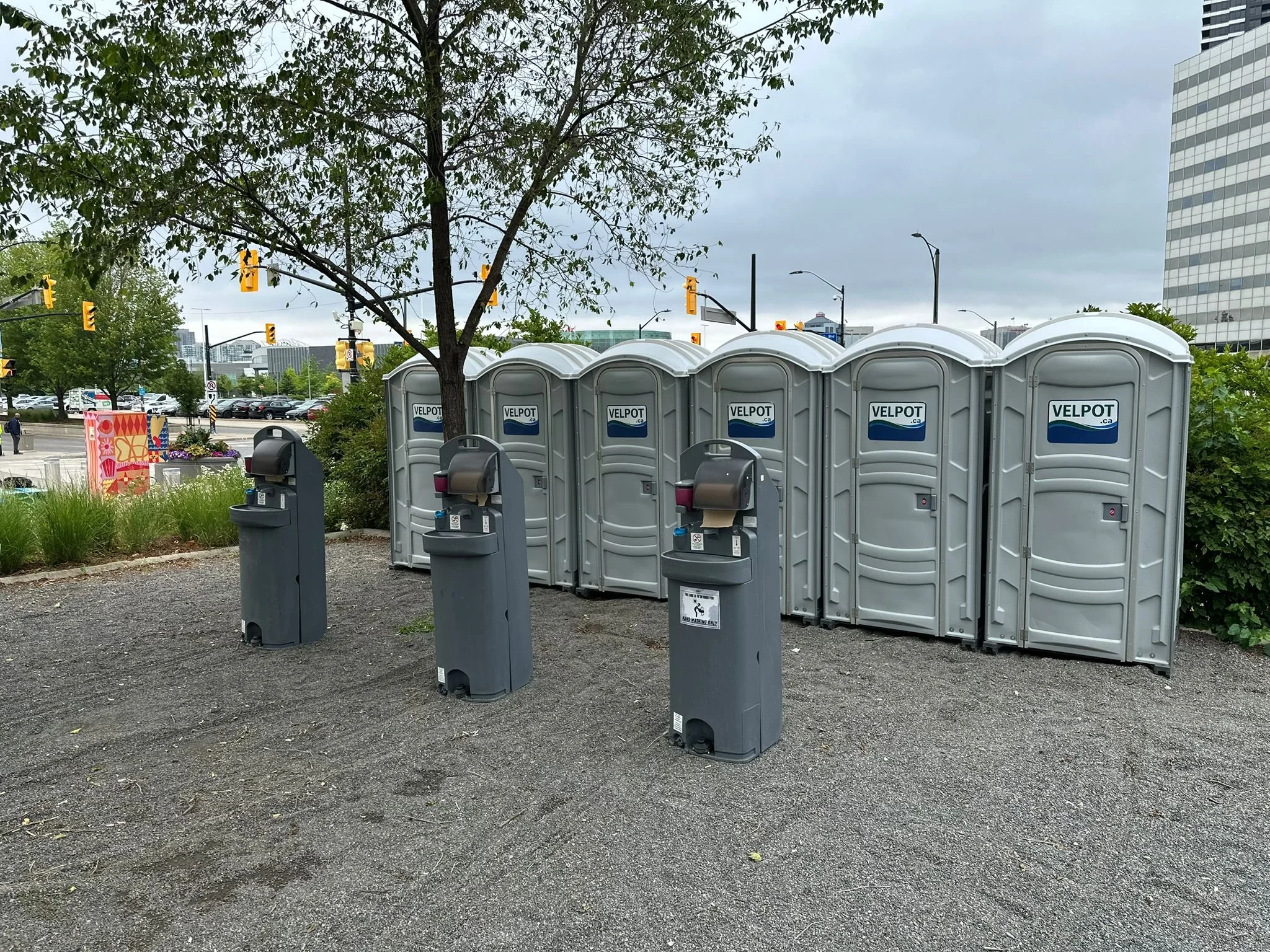 Grey portable toilets with portable handwash sink station at a festival.