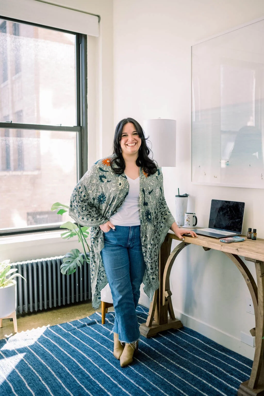 Pam Skop, owner and therapist at EveryBody Psychotherapy, standing at her desk and smiling at camera