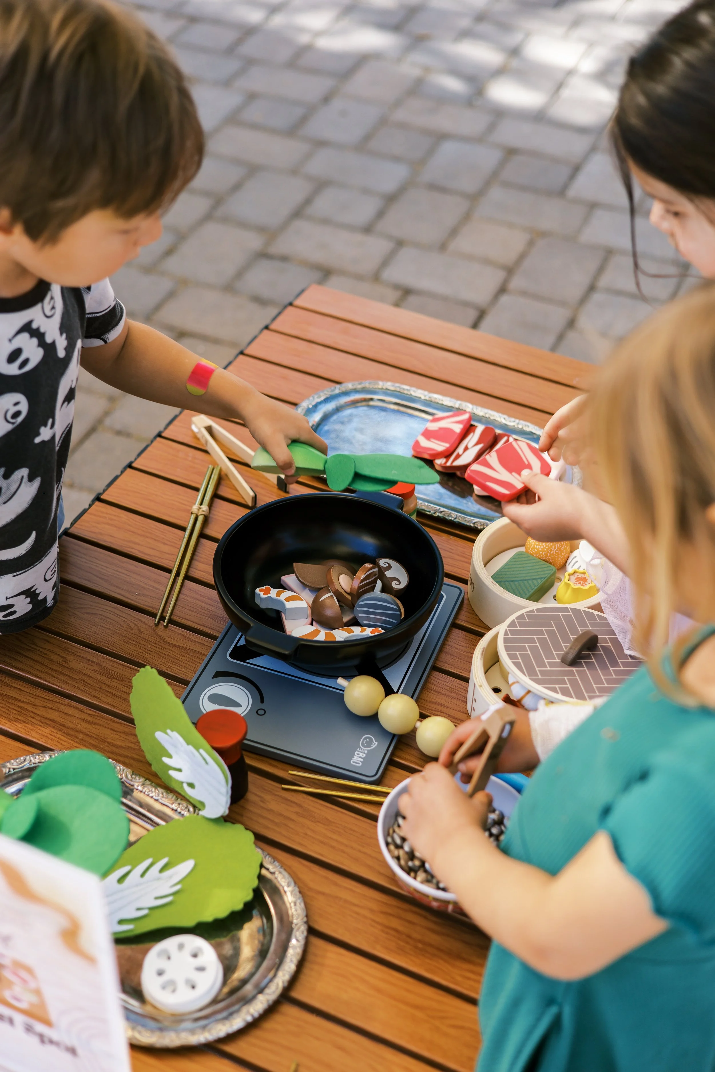 Children playing with toy kitchen set at Zoomies Play Cafe sensory play area, encouraging imaginative and social play.