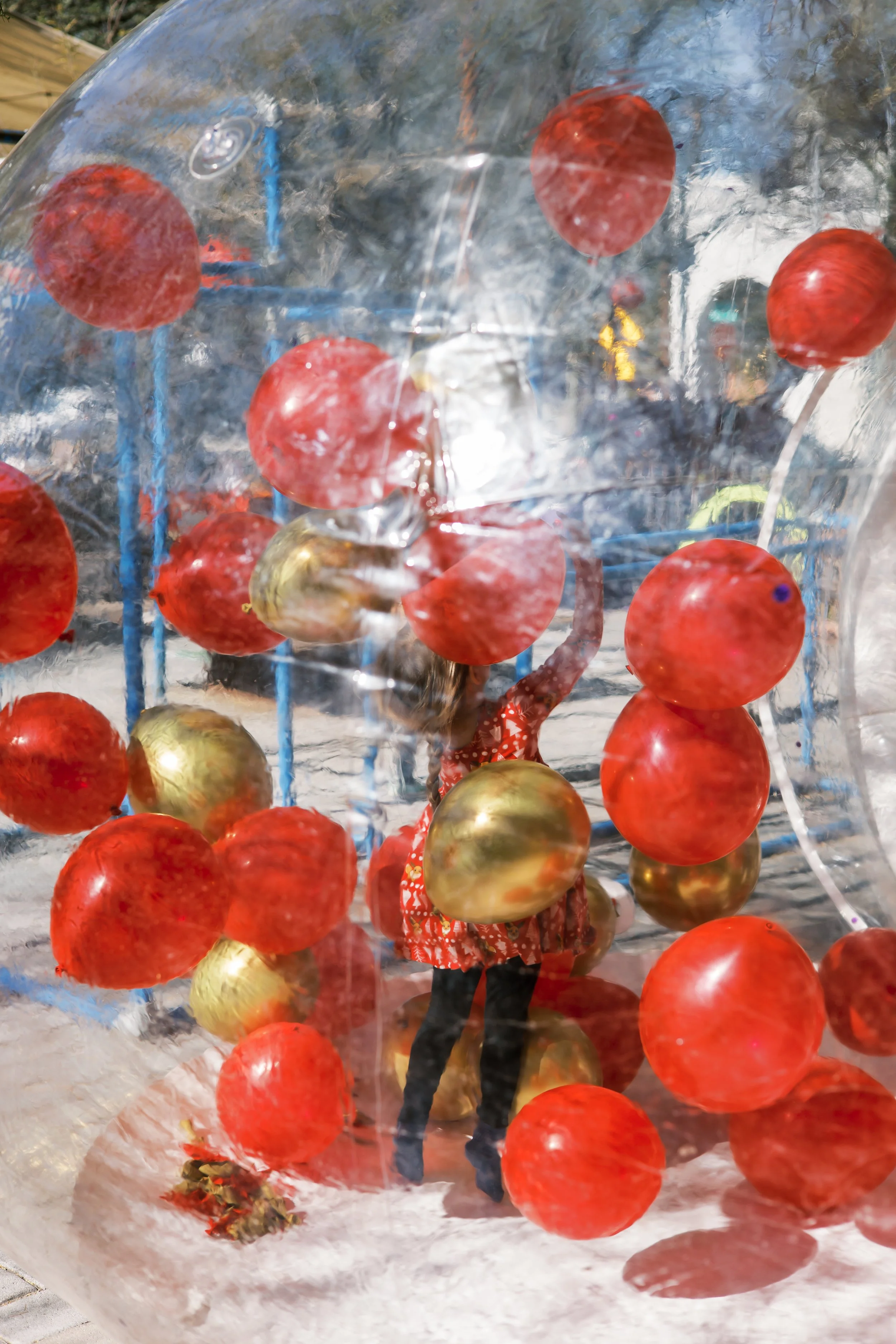 Child playing inside inflatable balloon dome at outdoor kids event hosted by Zoomies Play Cafe party services.