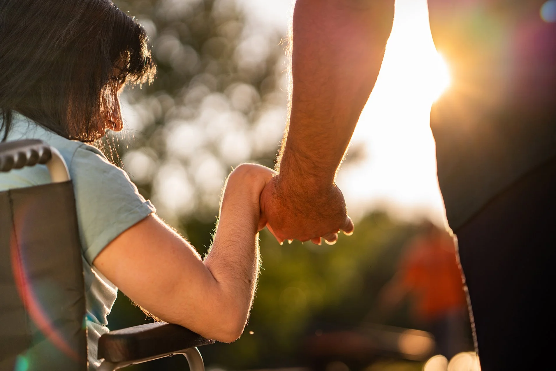 Woman in wheelchair holding a caregiver's hand
