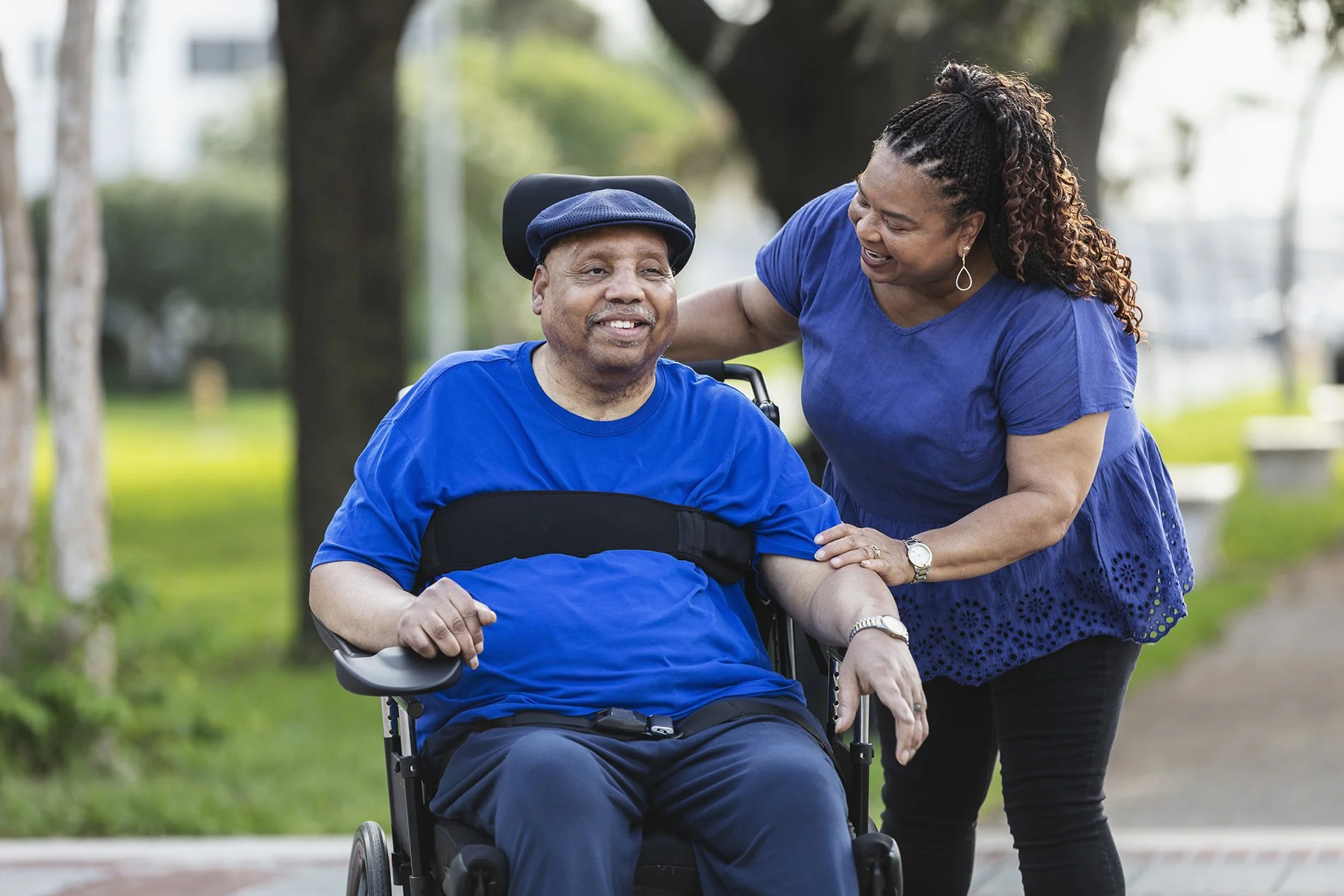 African American man with special needs in a wheelchair enjoying time outside with his caregiver