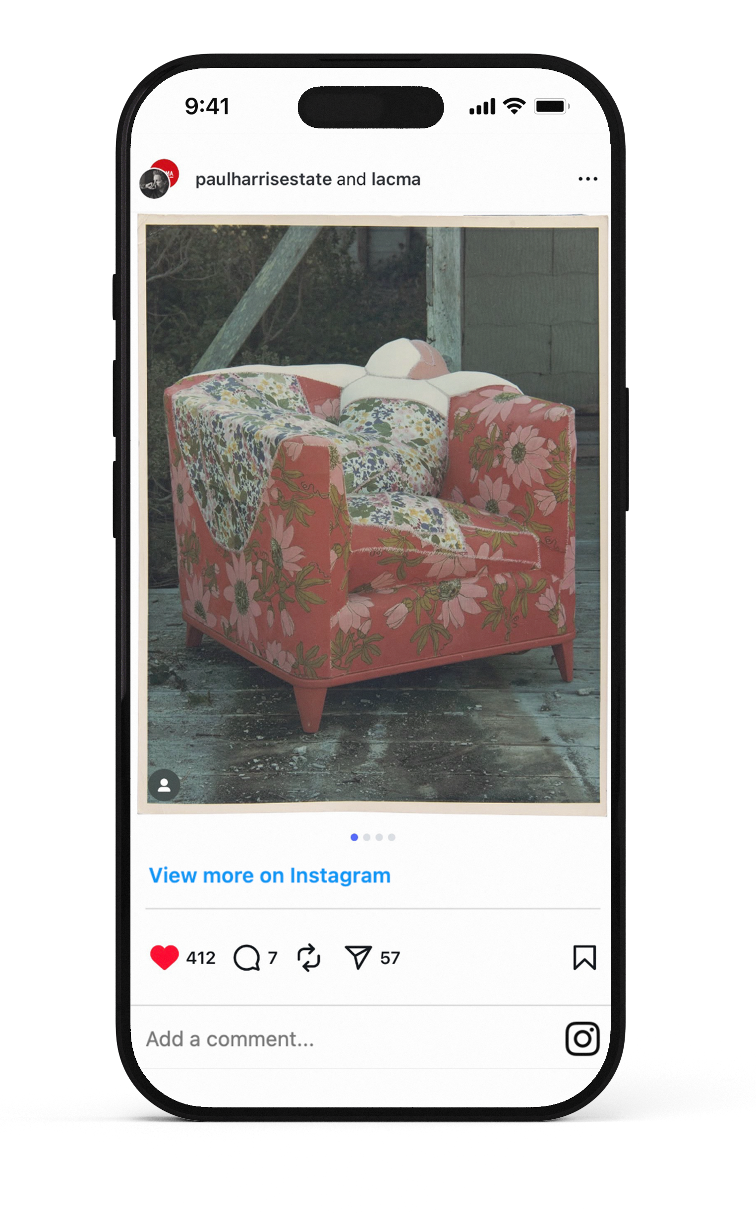 A pink armchair with a floral pattern, placed outdoors on a wooden deck, with some fabric draped over one arm.