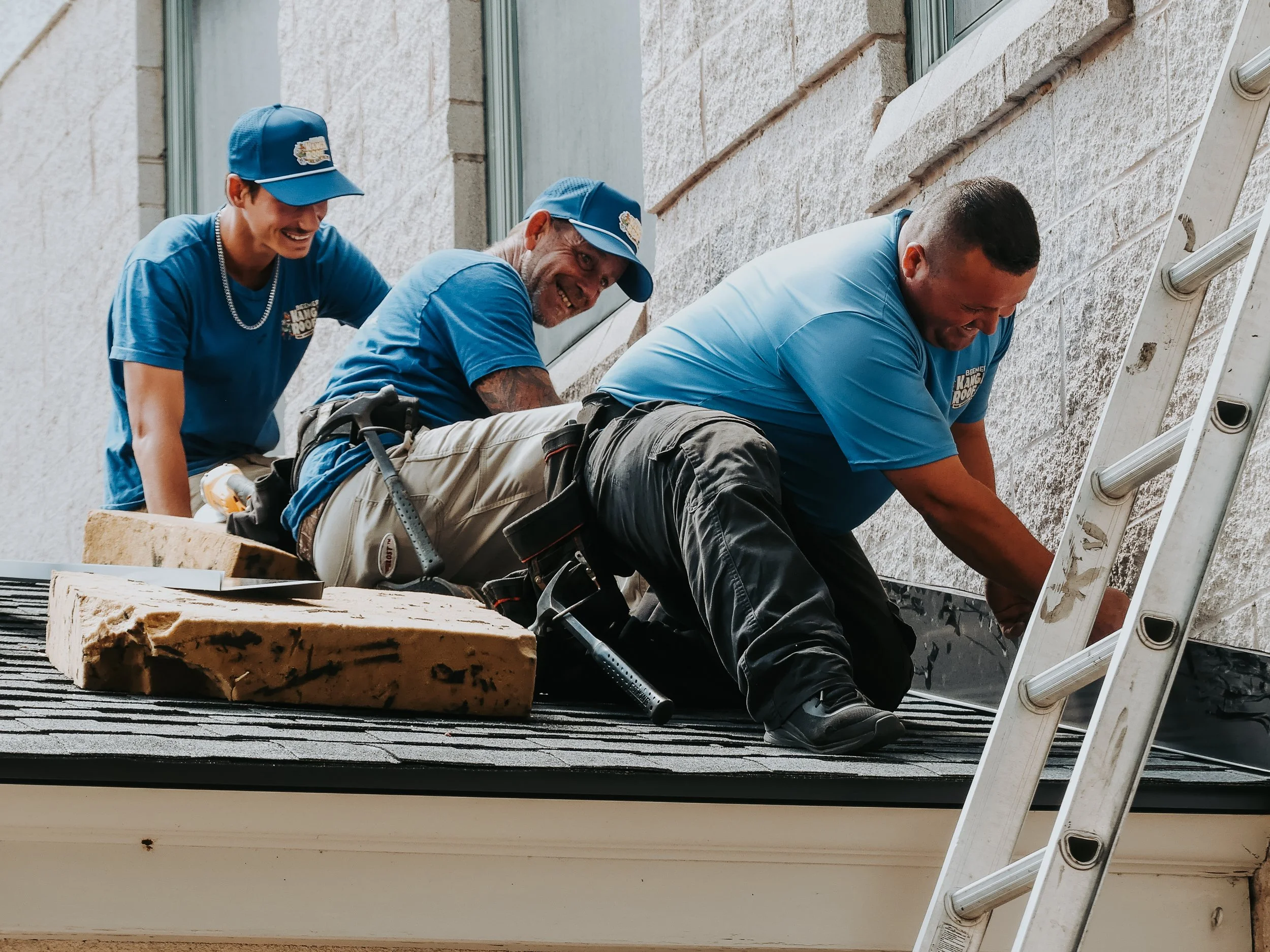 Three construction workers working on a roofing project, smiling and laughing together.