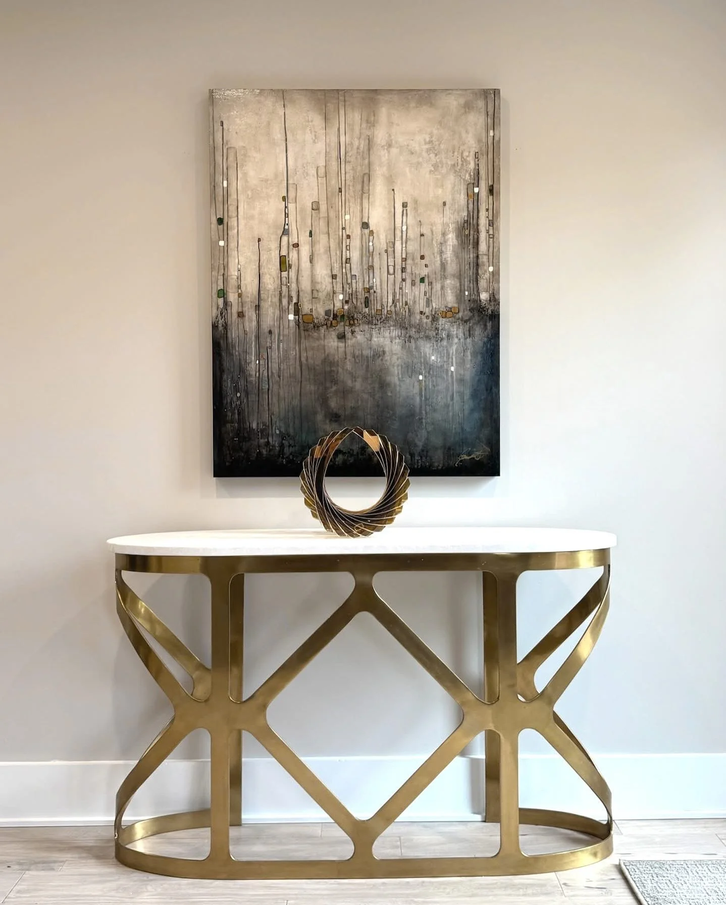 Elegant entryway featuring a gold geometric console table, circular metal sculpture, and abstract black-and-gold wall art.