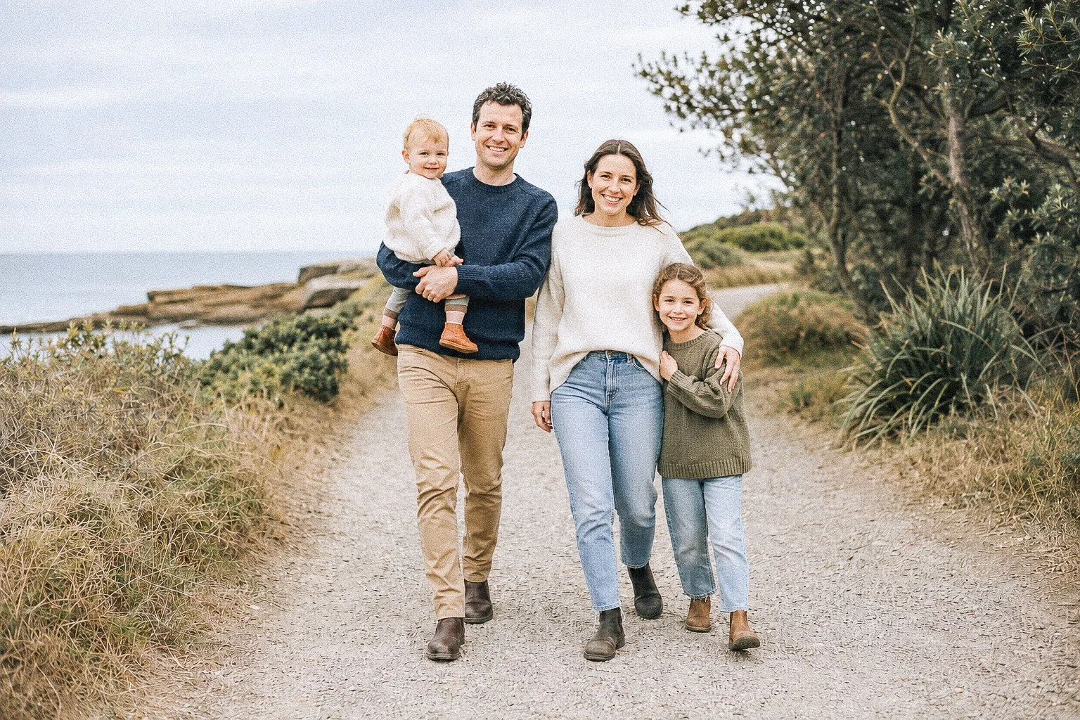 Parents walking along a coastal path with their two young children