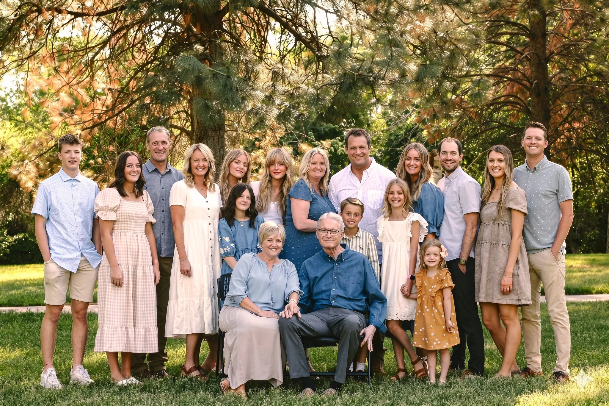 Extended family gathered together for a formal outdoor group portrait in a park setting.