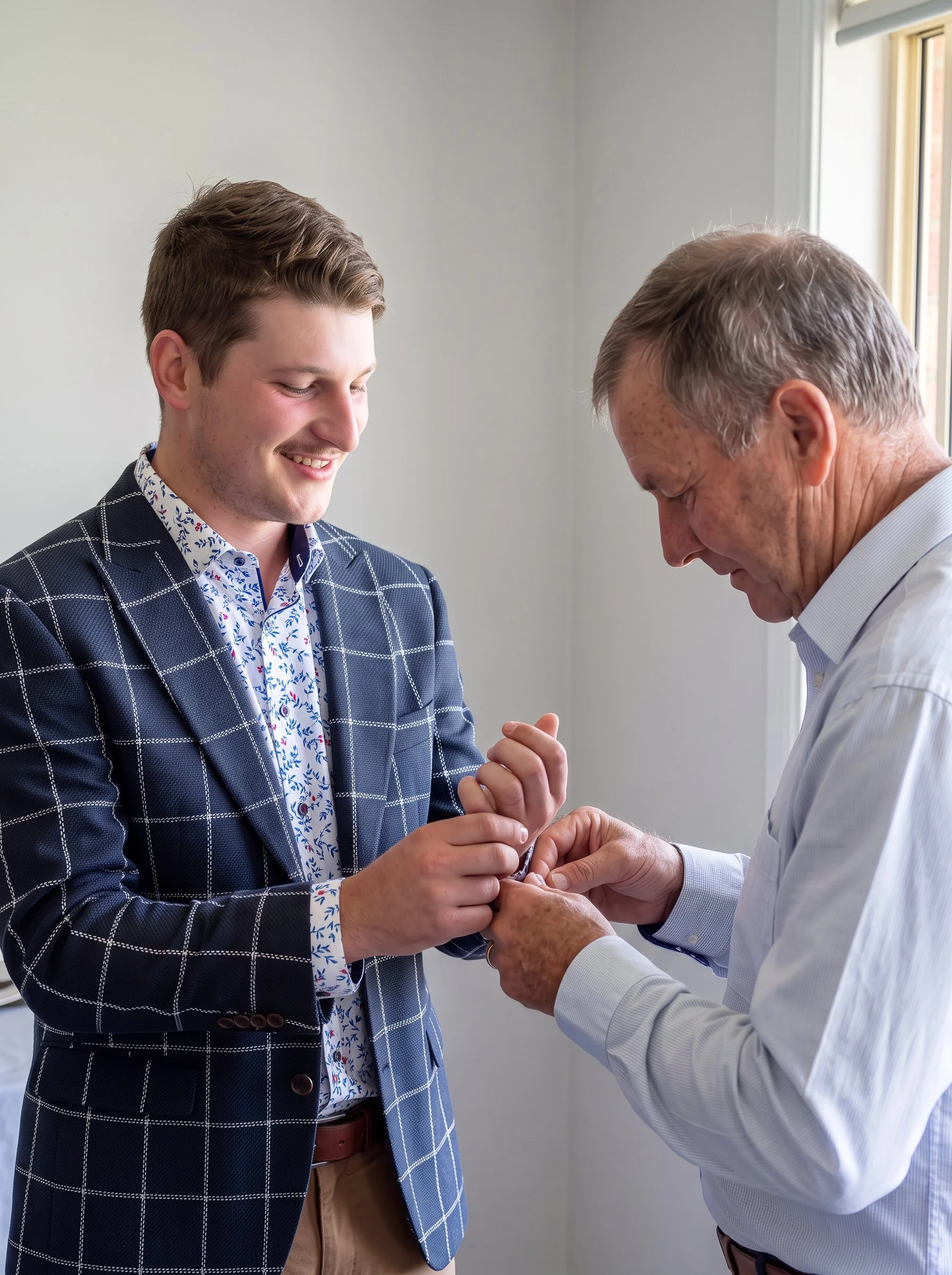  Family member helping the groom fasten his cuff before the wedding. 