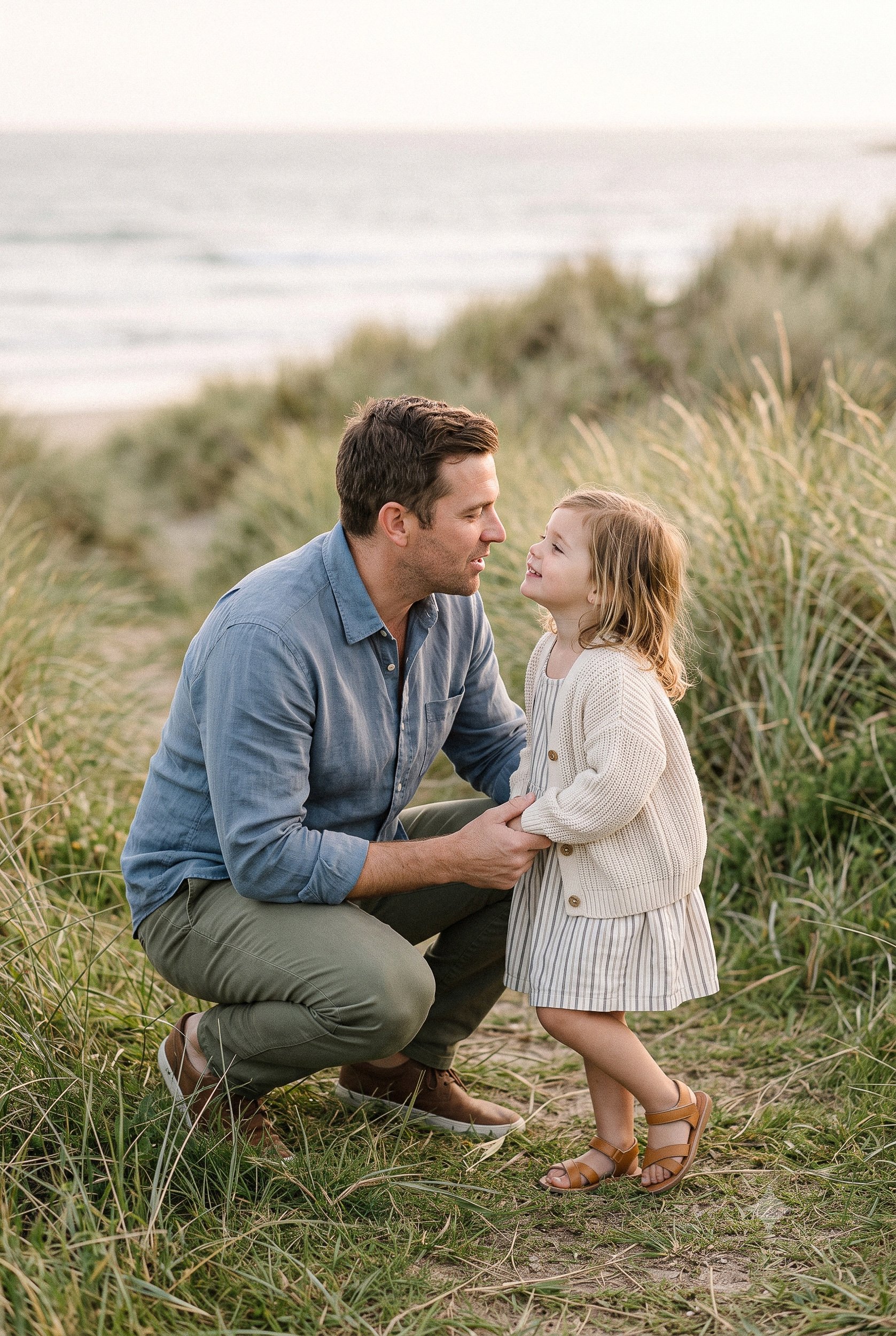  Parent crouching beside a young child in long grass 