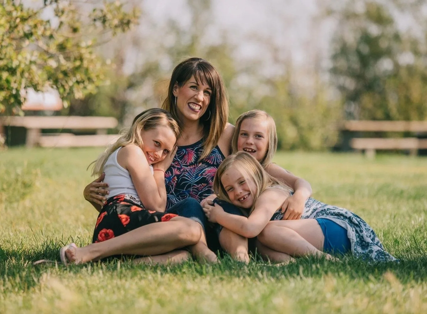Mother sitting on the grass with three children during a relaxed outdoor family portrait session.