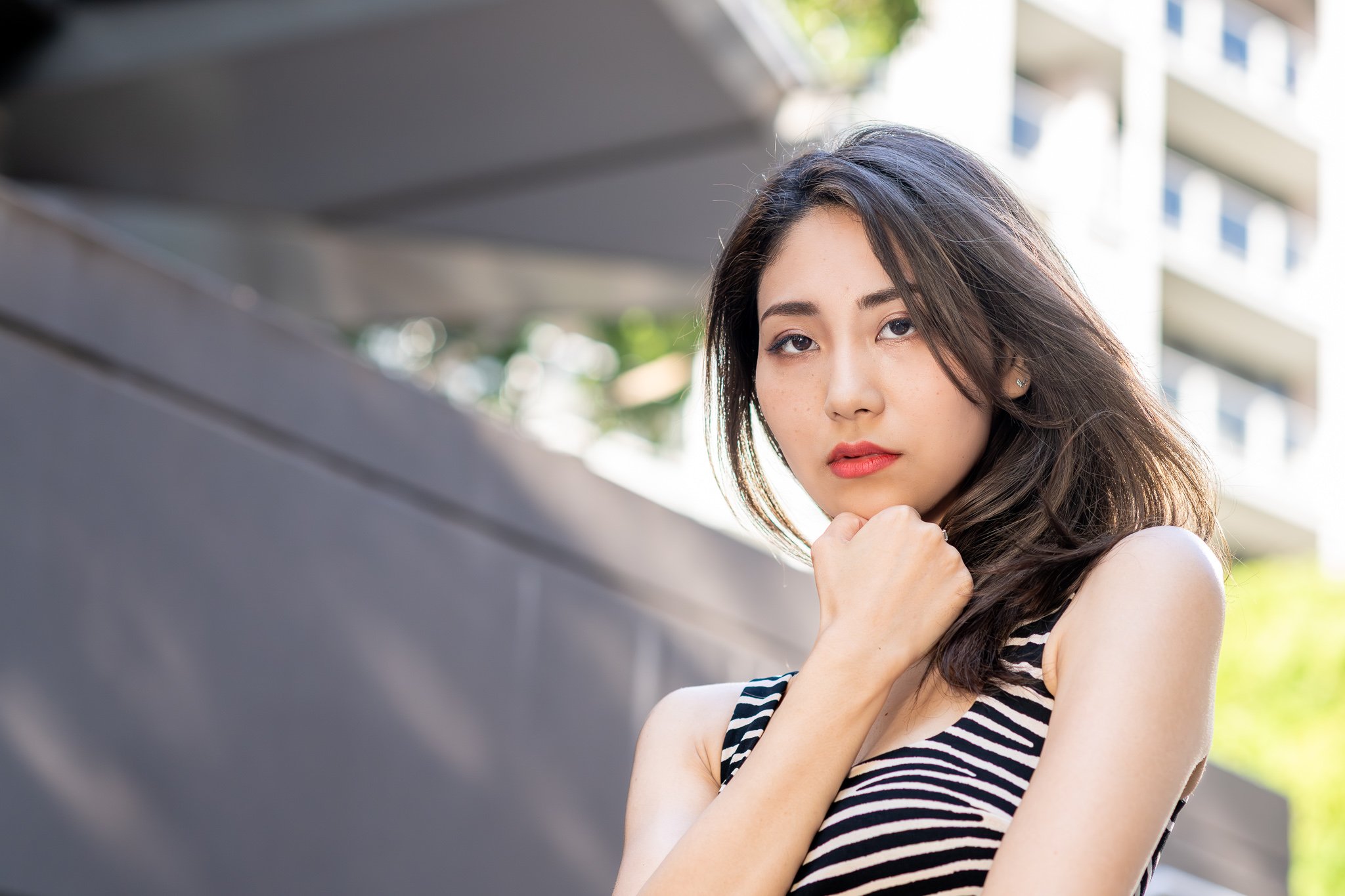 Woman posing for an outdoor lifestyle portrait in an urban setting with a softly blurred background.