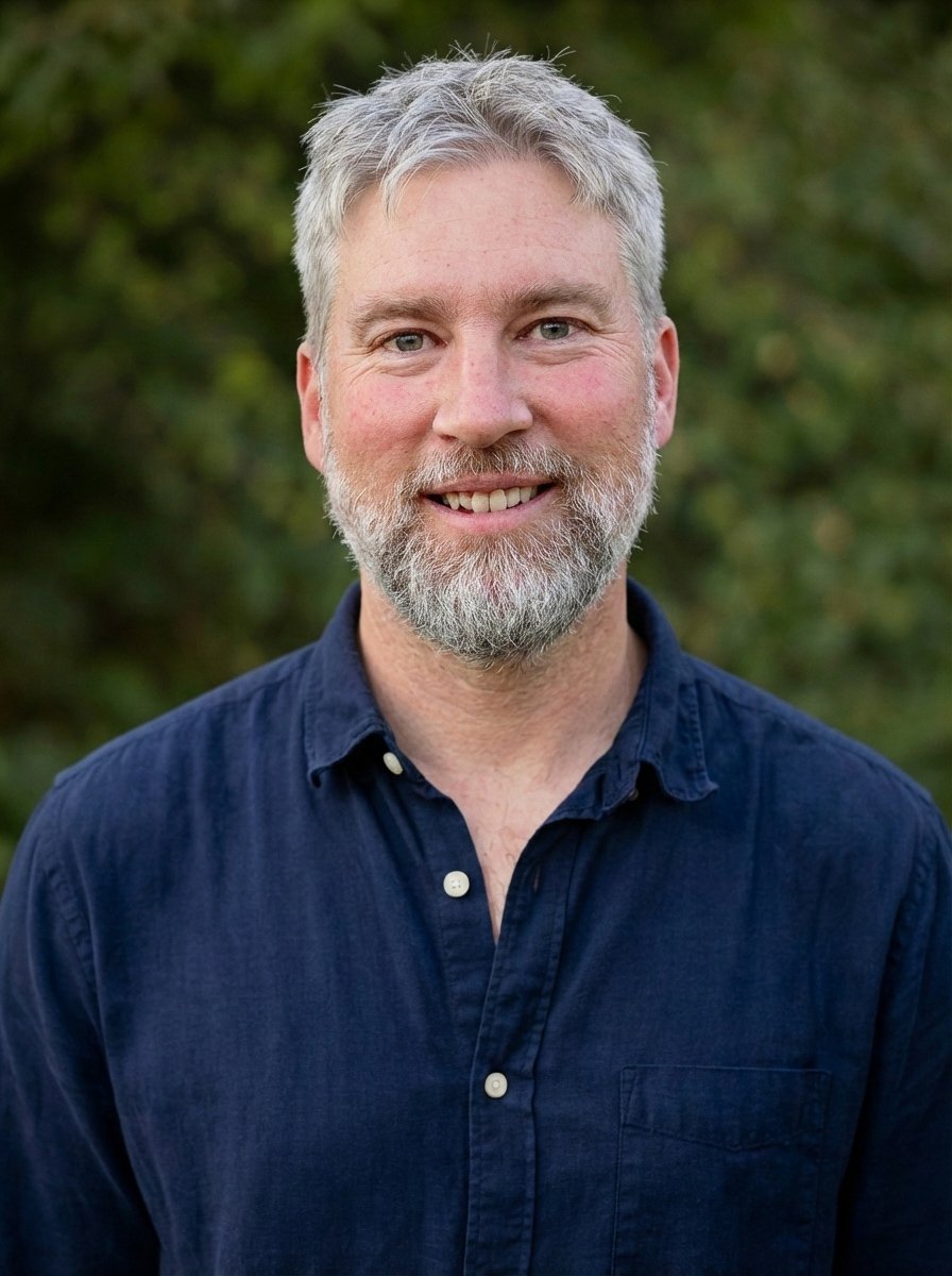 Portrait of Clinton, the photographer behind Water Cloud Images, standing outdoors against a natural green background.