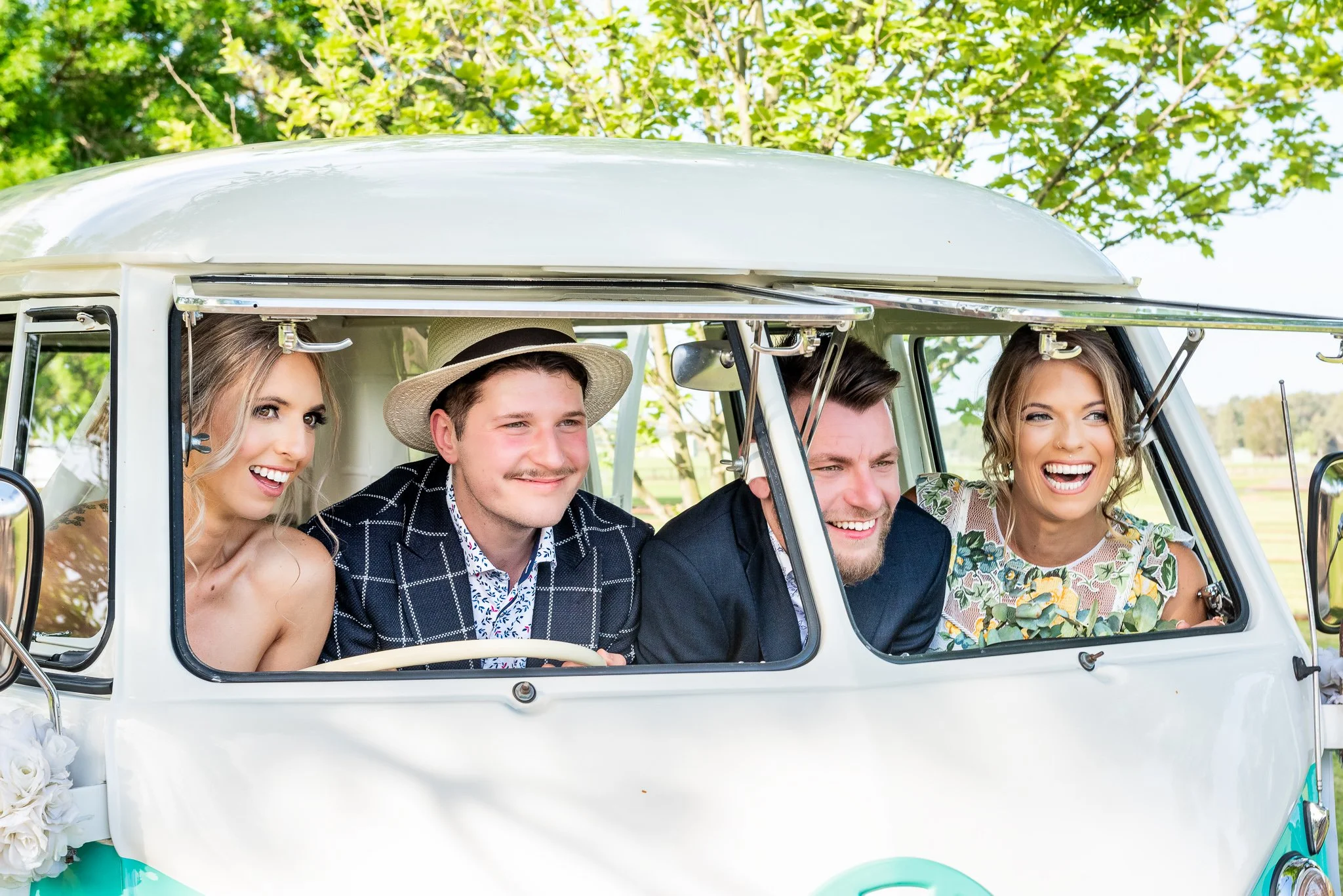 Bride, groom and wedding party sitting together inside a vintage wedding car.