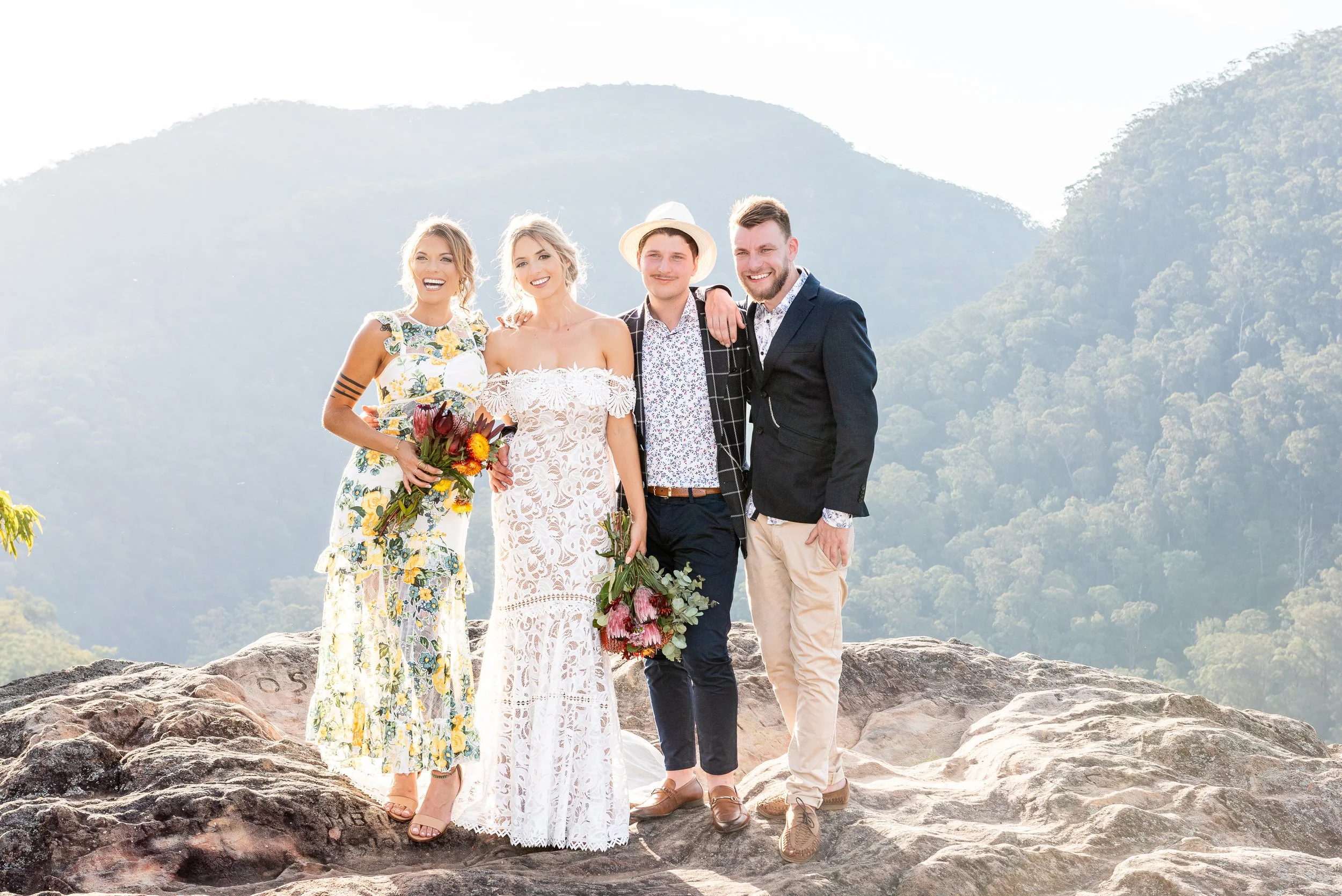 Wedding party standing together for an outdoor portrait with a mountain landscape in the background.