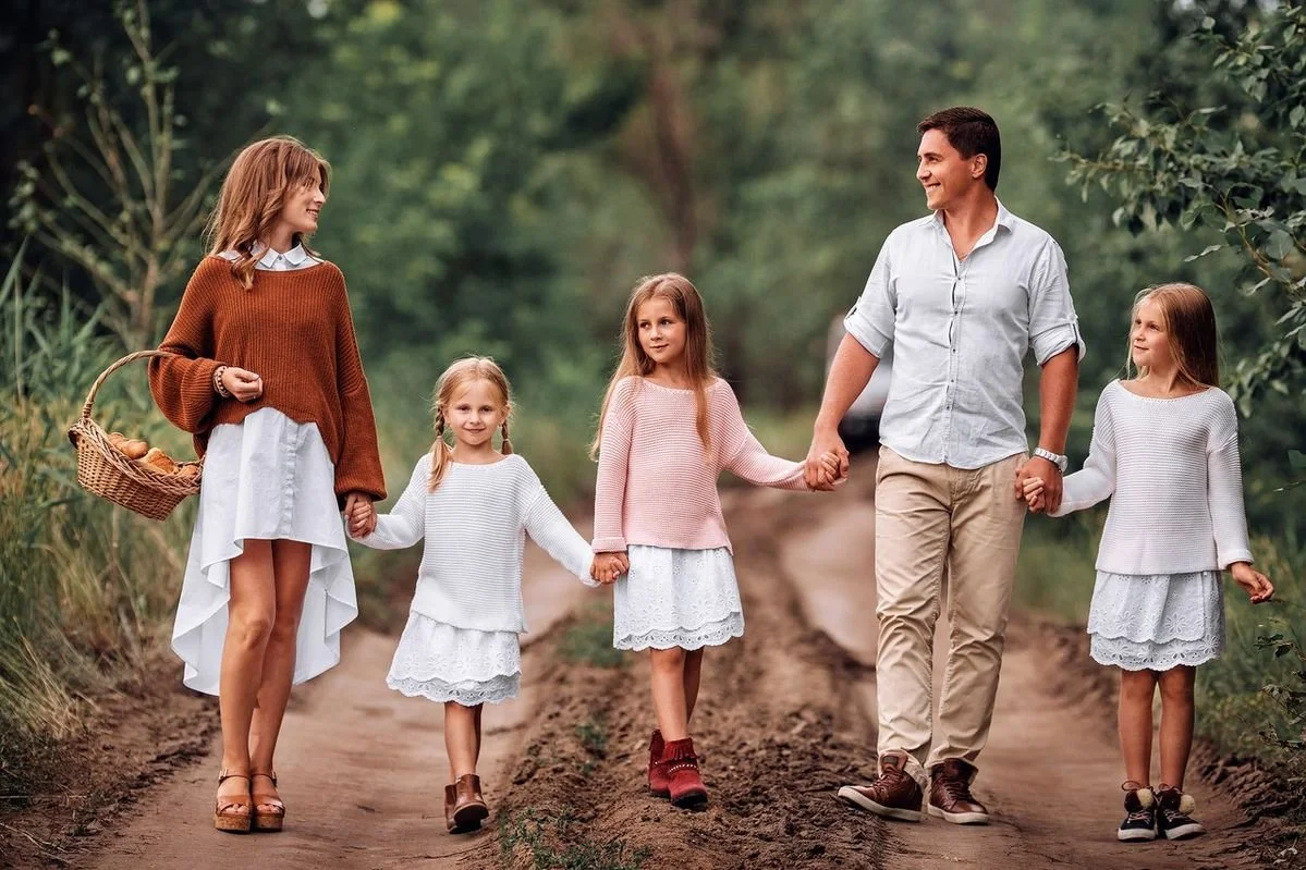Family holding hands while walking together along an outdoor track during a relaxed portrait session.