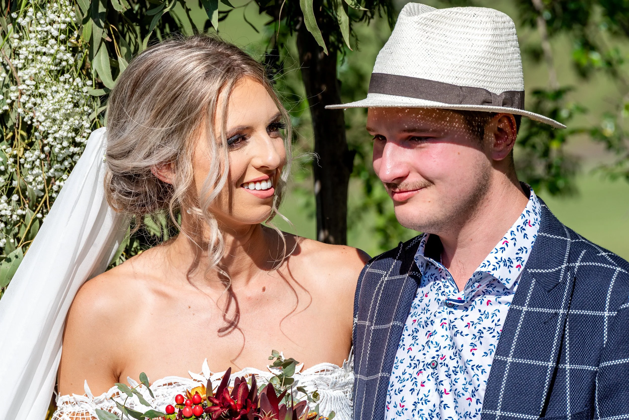 Bride and groom smiling together during a close-up outdoor wedding portrait.