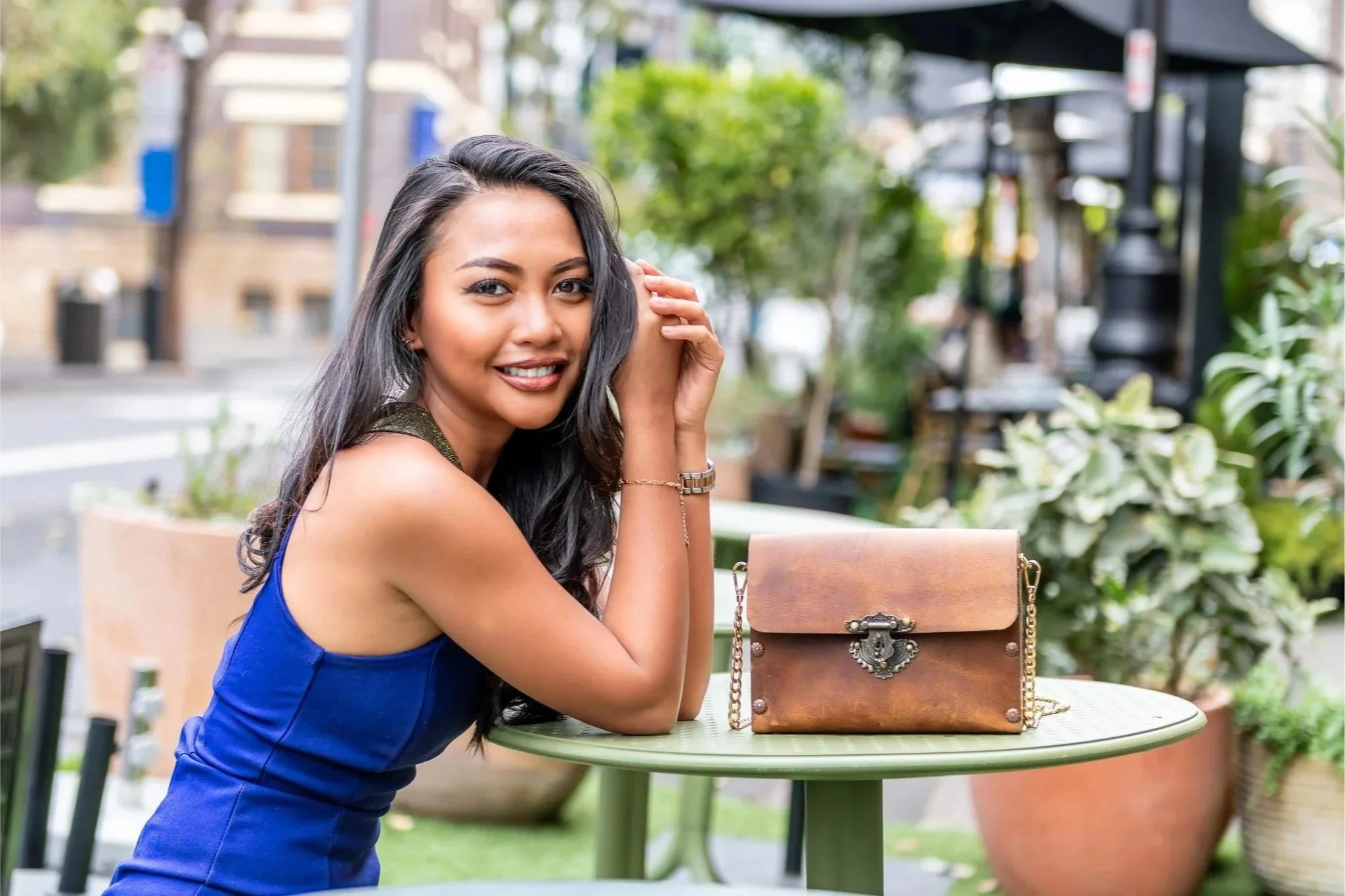 Woman seated at an outdoor cafe table during a lifestyle branding portrait session.